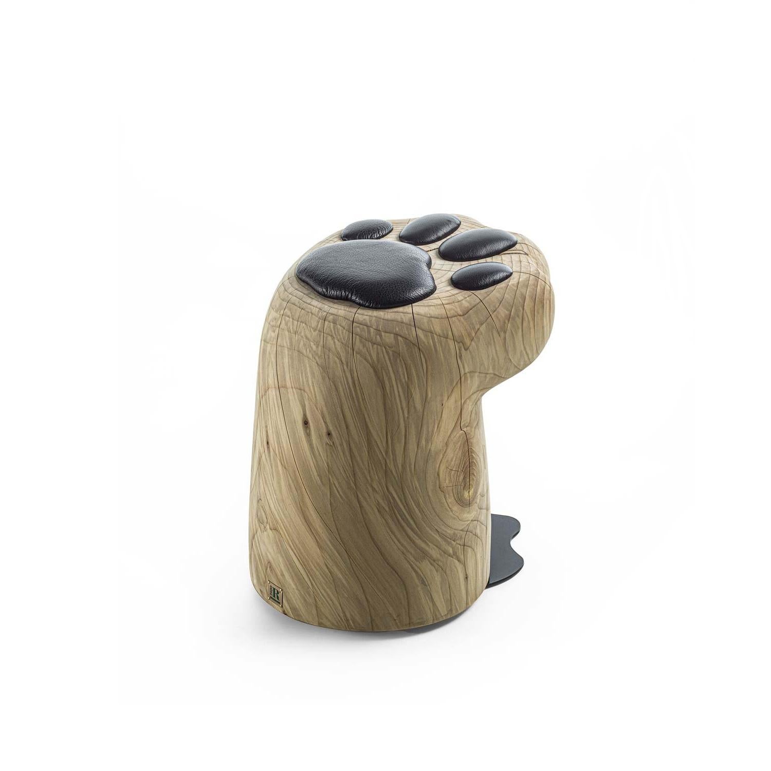 This unique stool, made from a single block of solid, fragrant reclaimed cedar wood, draws its design from the soft shape of a cat's paw. The seat features padded cushions in fabric or leather, shaped to resemble feline paw pads. 
This product is