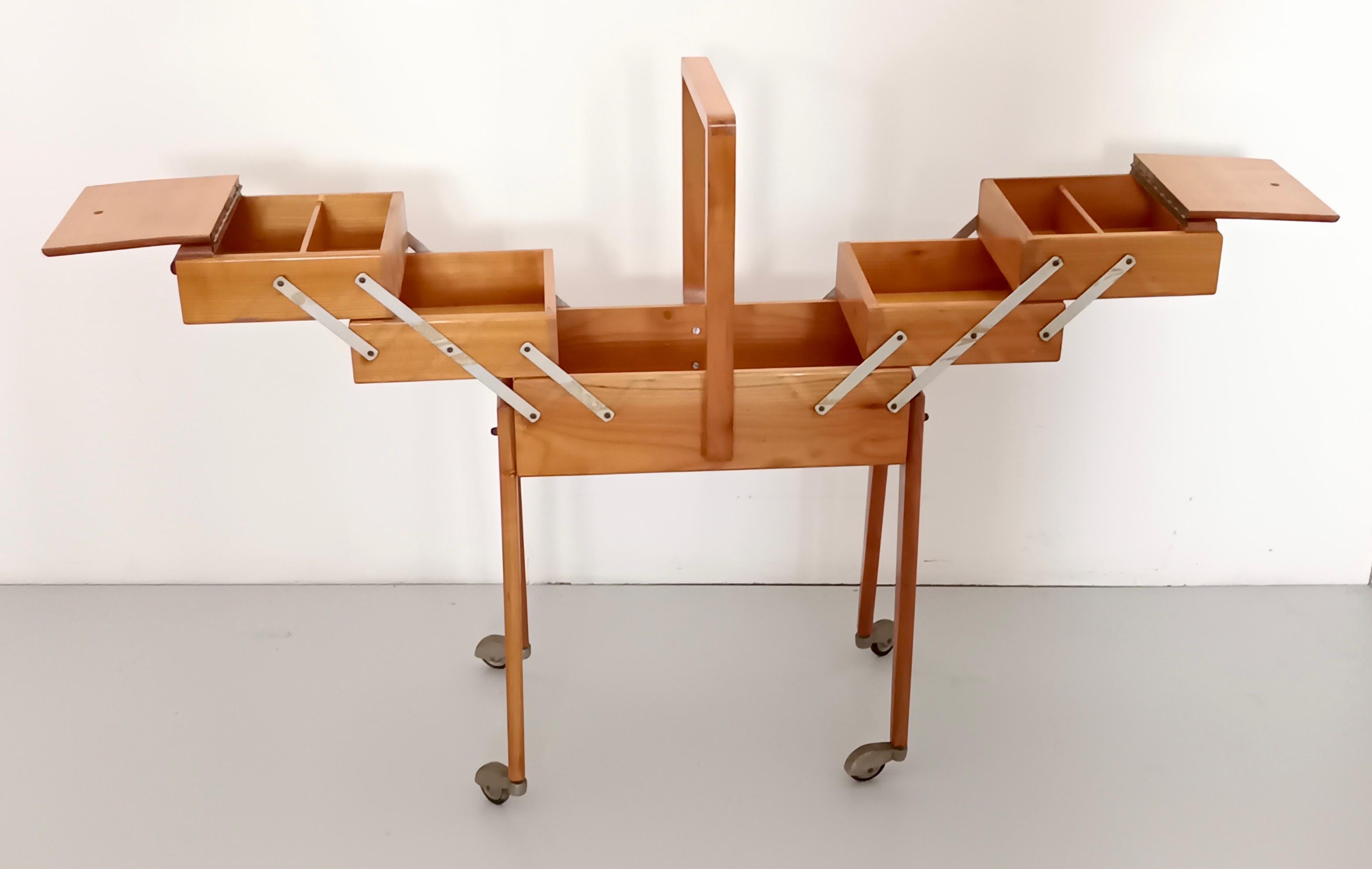 Made in Italy, 1950s. 
This standing sewing cabinet is made in solid cherrywood and features casters and silver-colored metal details.
It is a vintage piece, therefore it might show slight traces of use, but it can be considered as in very good