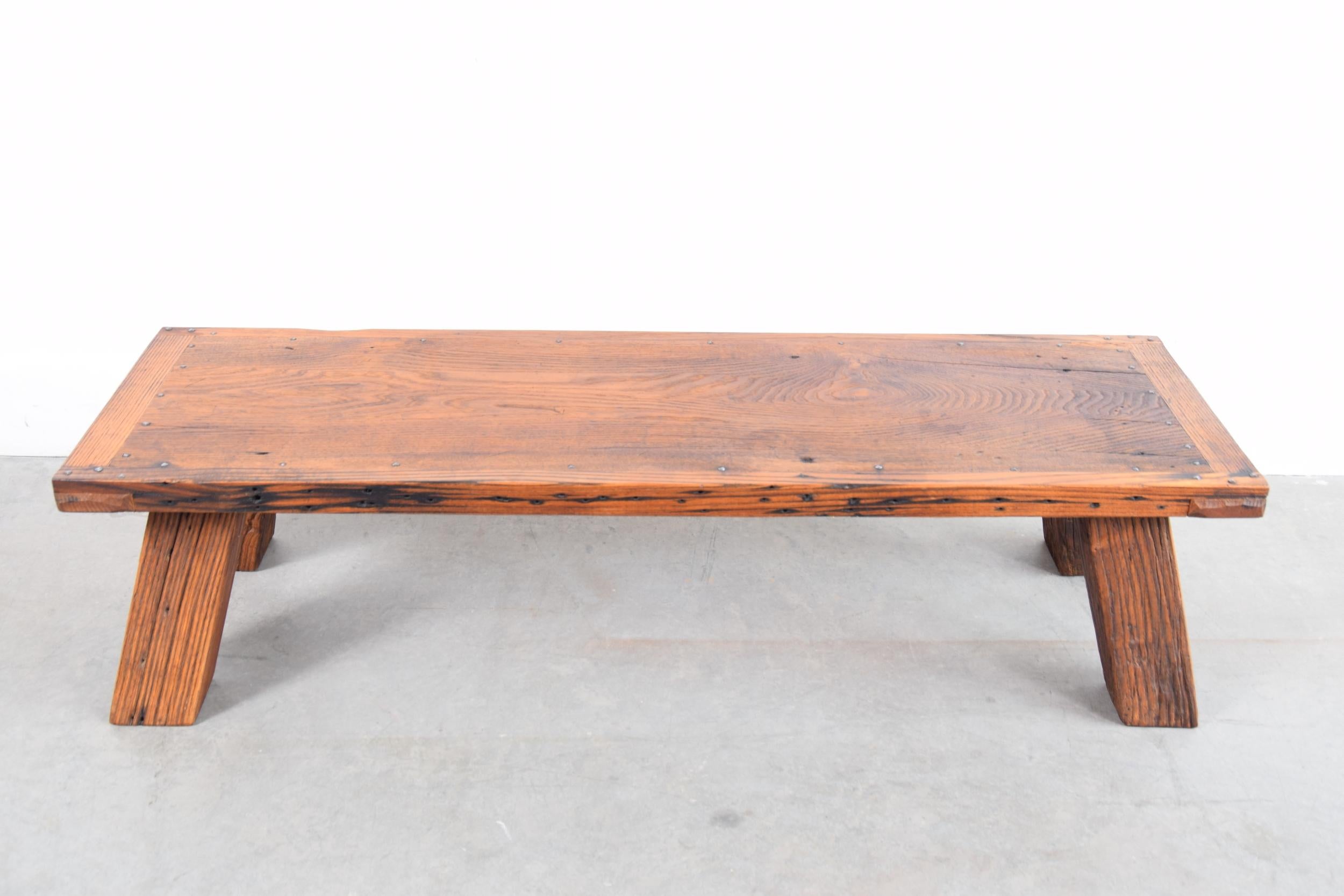 Coffee table constructed of re-claimed, solid North American chestnut. Very well constructed. One leg is notched out (a construction detail from whatever building this chestnut was salvaged from) on one corner. This Chestnut is likely 100 - 150