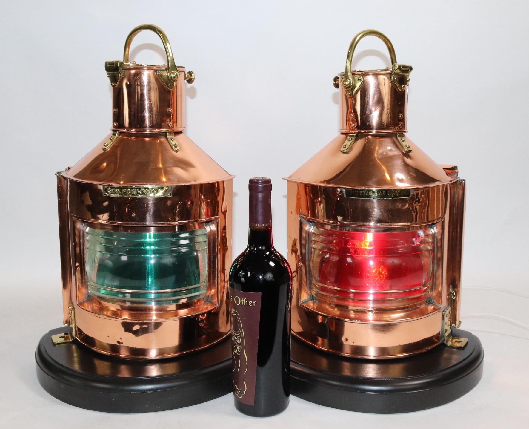 Highly polished copper and brass ships lanterns by Anderson and Gyde of England. With clear glass fresnel lenses, removable red and green filters, brass bezels and hinges, mounted to thick wood bases with dark finish. Both lanterns have been