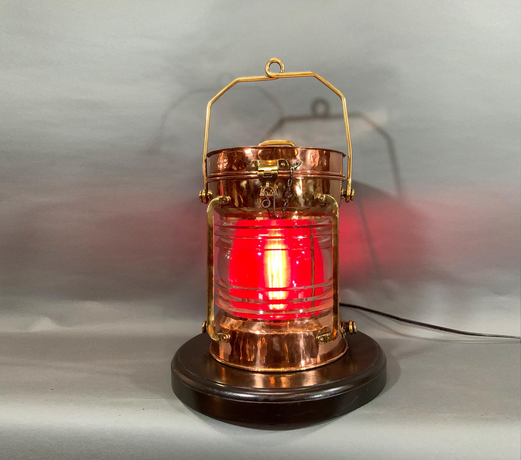 This is a “not under command” lantern with brass badges, hasp, hinge, handle, bars, etc. Glass Fresnel lens with removable red filter. Wired with a new socket. Mounted to a thick mahogany base. Condition good. The removable red filter has