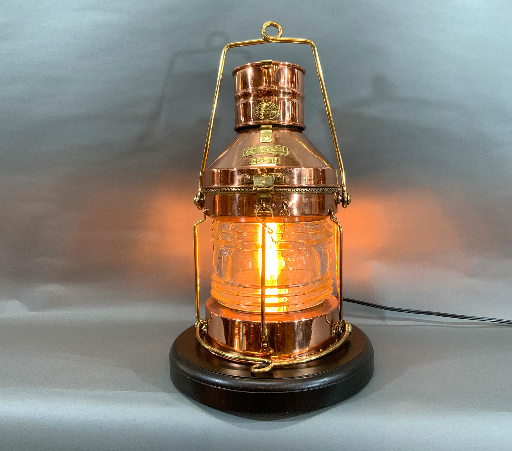 Antique highly polished solid copper ships lantern with brass trim. Hinged top. Brasses include hinges, hasp, hook, bars, handles, etc. Fitted to a varnished mahogany base. Wired with electric for home use. With brass badge from Chandler. The very