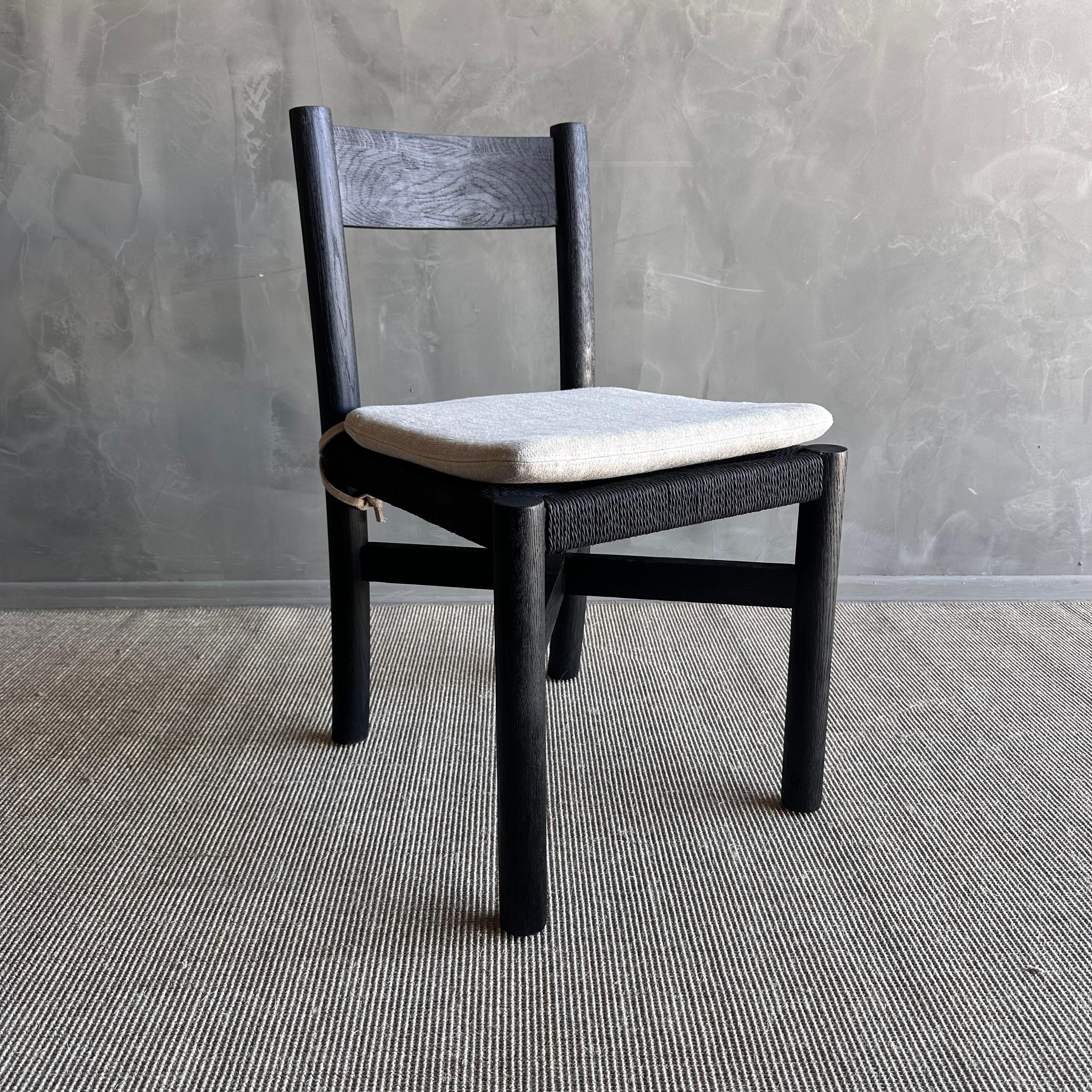 The Ellie Ebonized dining chair is a stunning piece crafted from solid white oak, elegantly stained with ebony for a rich, luxurious finish. The beautiful grain texture of the wood is prominently showcased, adding a touch of natural beauty to any