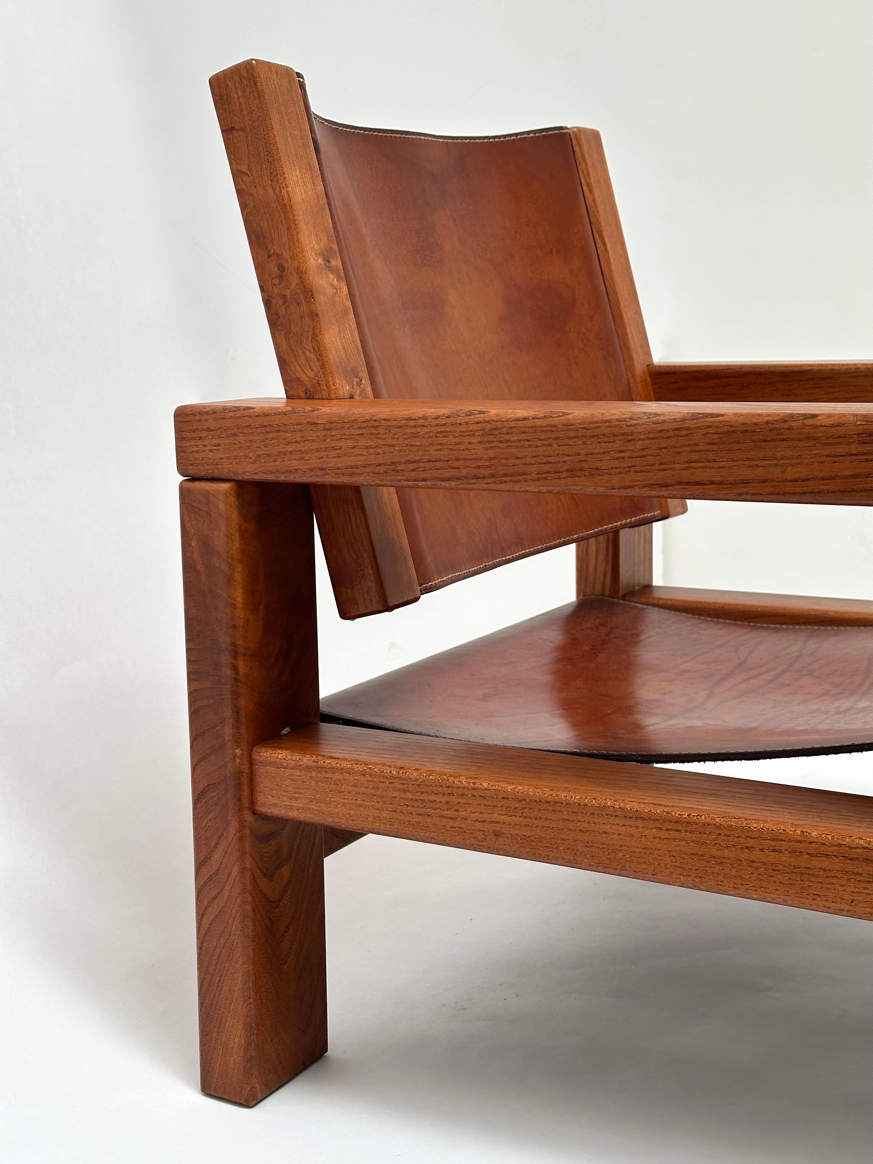 Eleganter Sessel aus massiver Ulme mit sehr ausgewogenen Proportionen.

Sitz und Rückenlehne aus gelbbraunem Leder bieten bemerkenswerten Komfort.

Dies ist eine der ersten Kreationen von Michel Milleret, Exklusivdesigner der Galerie l'Orme in