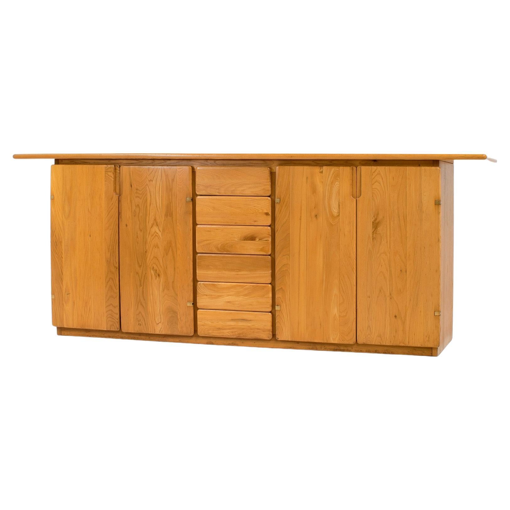 This elm sideboard was sourced in Italy and is produced by Romanutti in the 1970s. 
Because it is completely made of elm, it has a French feeling to it, but the rounded edges and the brass details give away its Italian origin. It is also less heavy