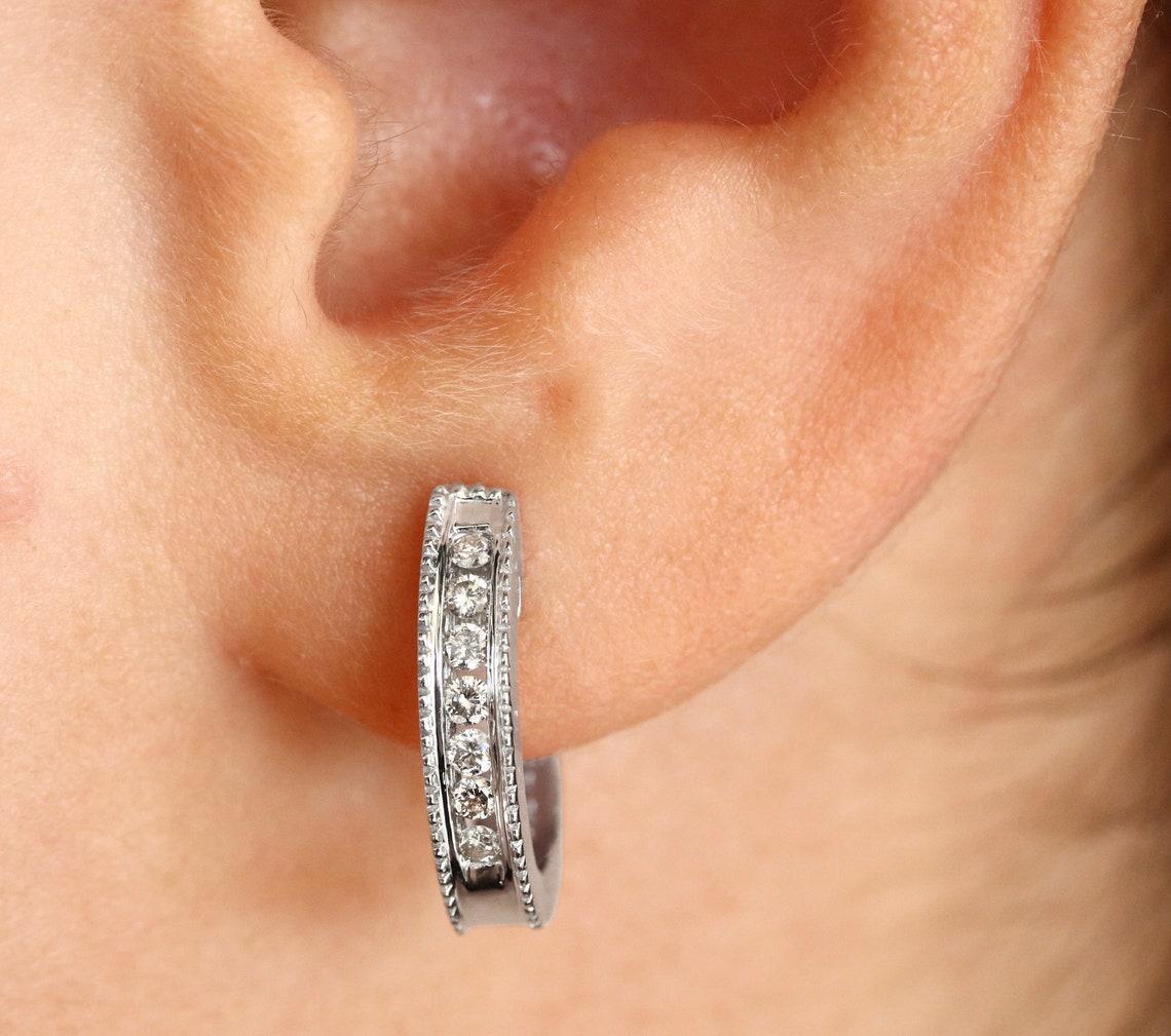 Un elegante par de pendientes de diamantes de estilo abrazador. Creados en glamuroso oro blanco de 14k, estos pendientes presentan siete diamantes redondos de alta calidad en cada aro. Estos diamantes naturales están totalmente facetados, lo que