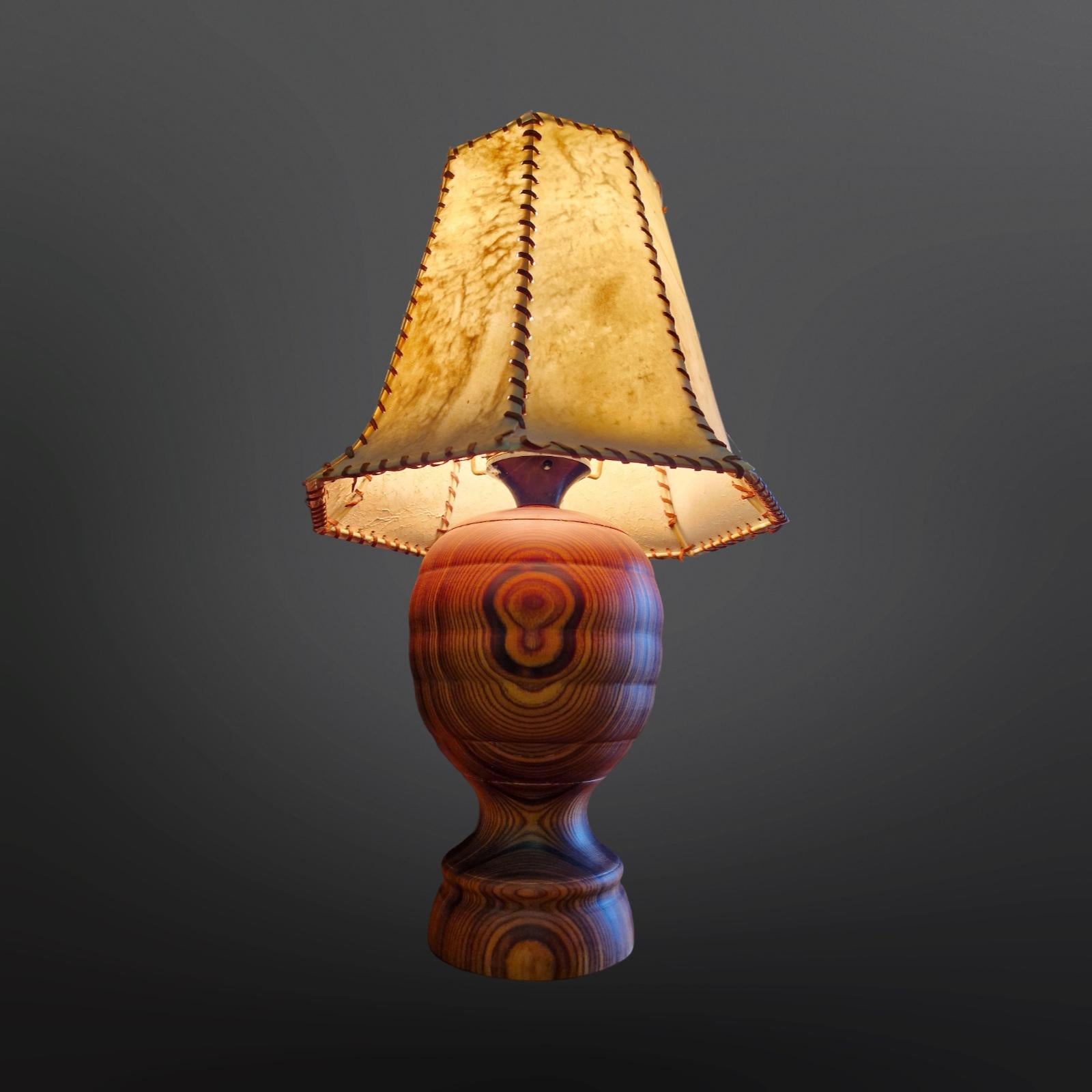 Lampe de table du milieu du siècle. La base est en bois dur tourné et l'abat-jour est en cuir animal. La base présente un magnifique motif de grain et des couleurs riches et profondes. 
L'abat-jour est fabriqué à partir de morceaux de cuir cousus