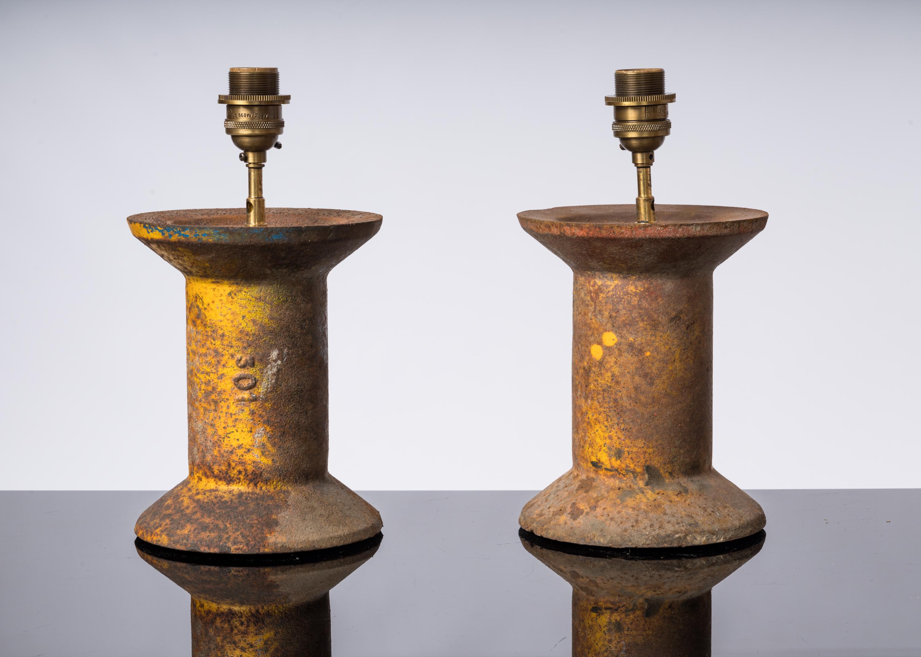 Pair of industrial cast steel lamps. Shaped like spools, these pieces were mounted as lamps with a notch at the base to allow the wire to pass through.
Traces of yellow paint are more pronounced on one than the other.
Original patina. They can be