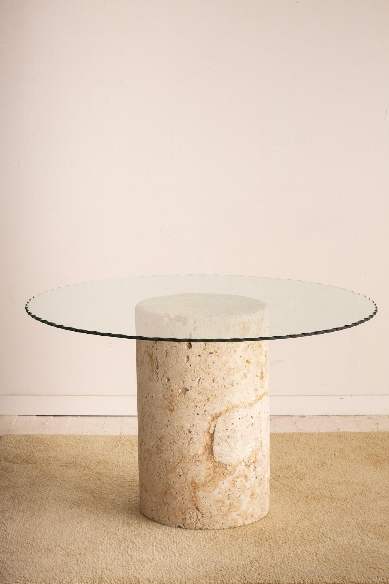 Solid limestone monolith dining table. Cylinder shaped base with scalloped edge glass top. Matte finish with wonderful texture and color variations throughout. Due to the nature of the stone minor losses are expected throughout. Please account for