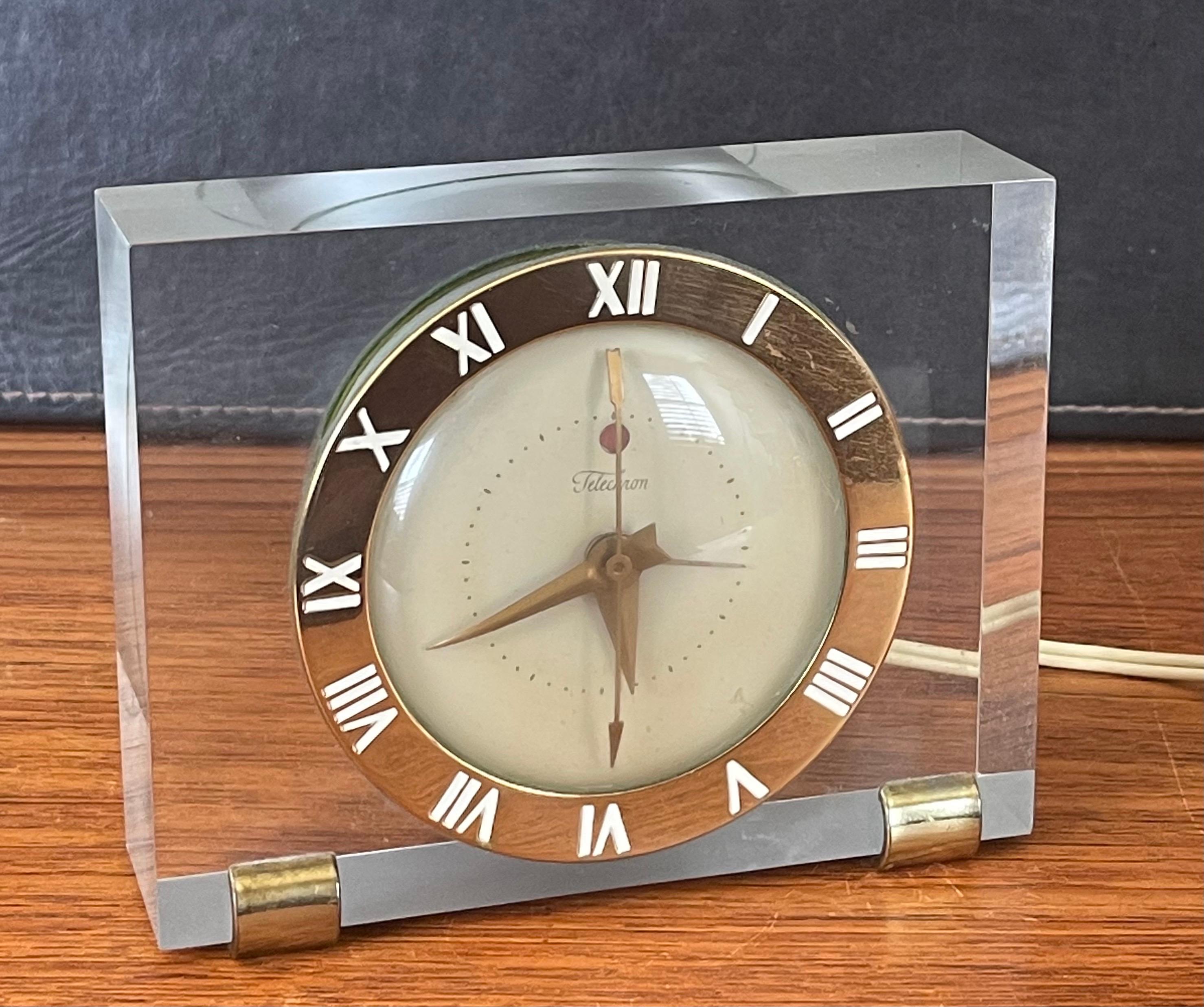 A gorgeous solid lucite with brass accents electric desk / mantel clock by Telechron, circa 1940s. The clock is in very good working condition and keeps accurate time. The brass dial has white Roman numerals and a cream colored face. Great art deco
