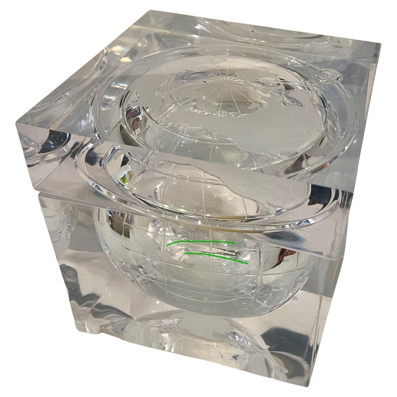 Preciosa cubitera de lucita maciza que representa el mundo plasmado en una escultura que se asemeja a un cubito de hielo. El efecto muestra un mapamundi esmerilado de continentes y orbitando la luna. Esta pieza fue diseñada y creada por Alessandro