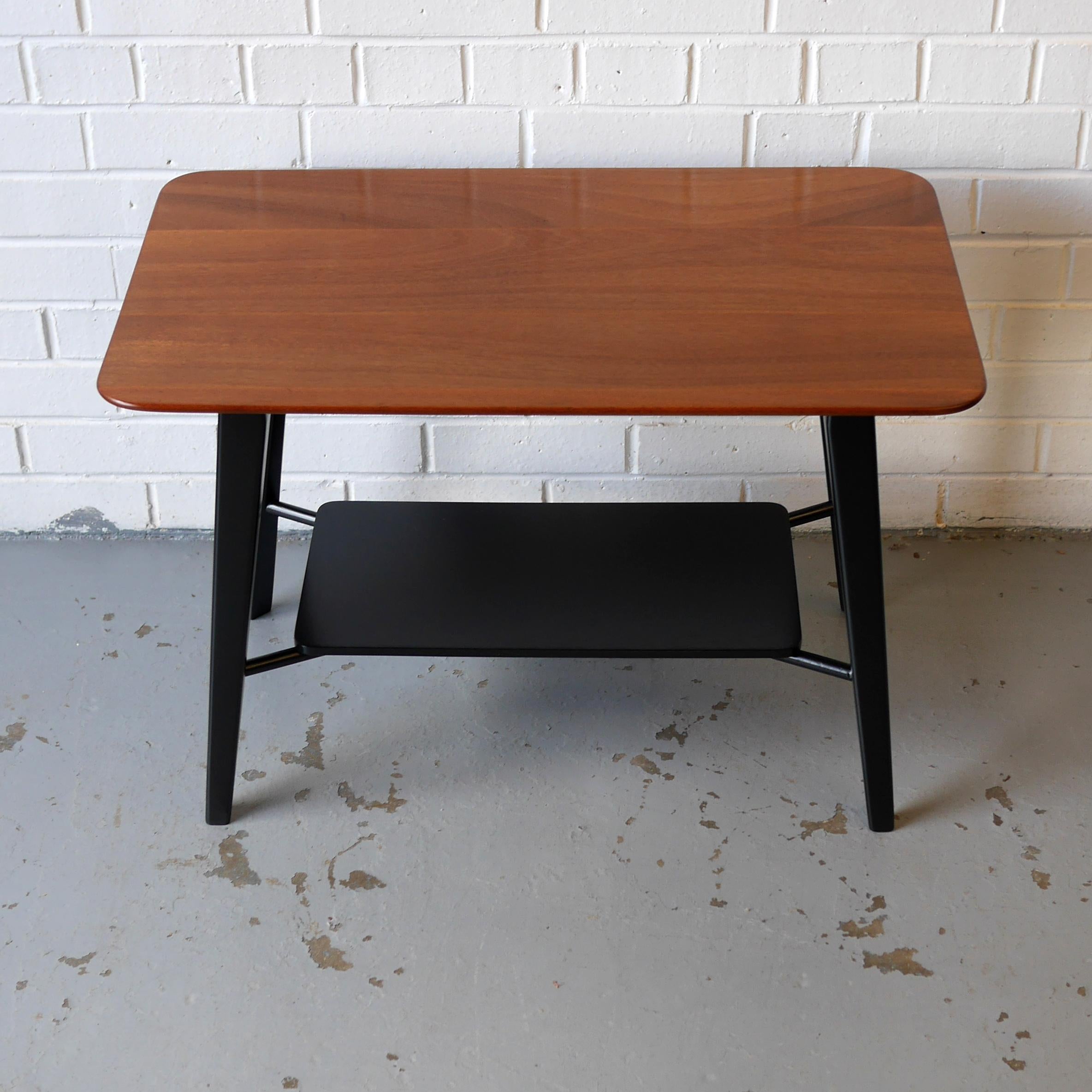 A super flexible coffee or lamp table by Peter Hayward for Vanson Furniture circa 1955 featuring a solid mahogany top with newly ebonised splayed legs and undershelf. The top is constructed from three solid planks of mahogany with rounded corners