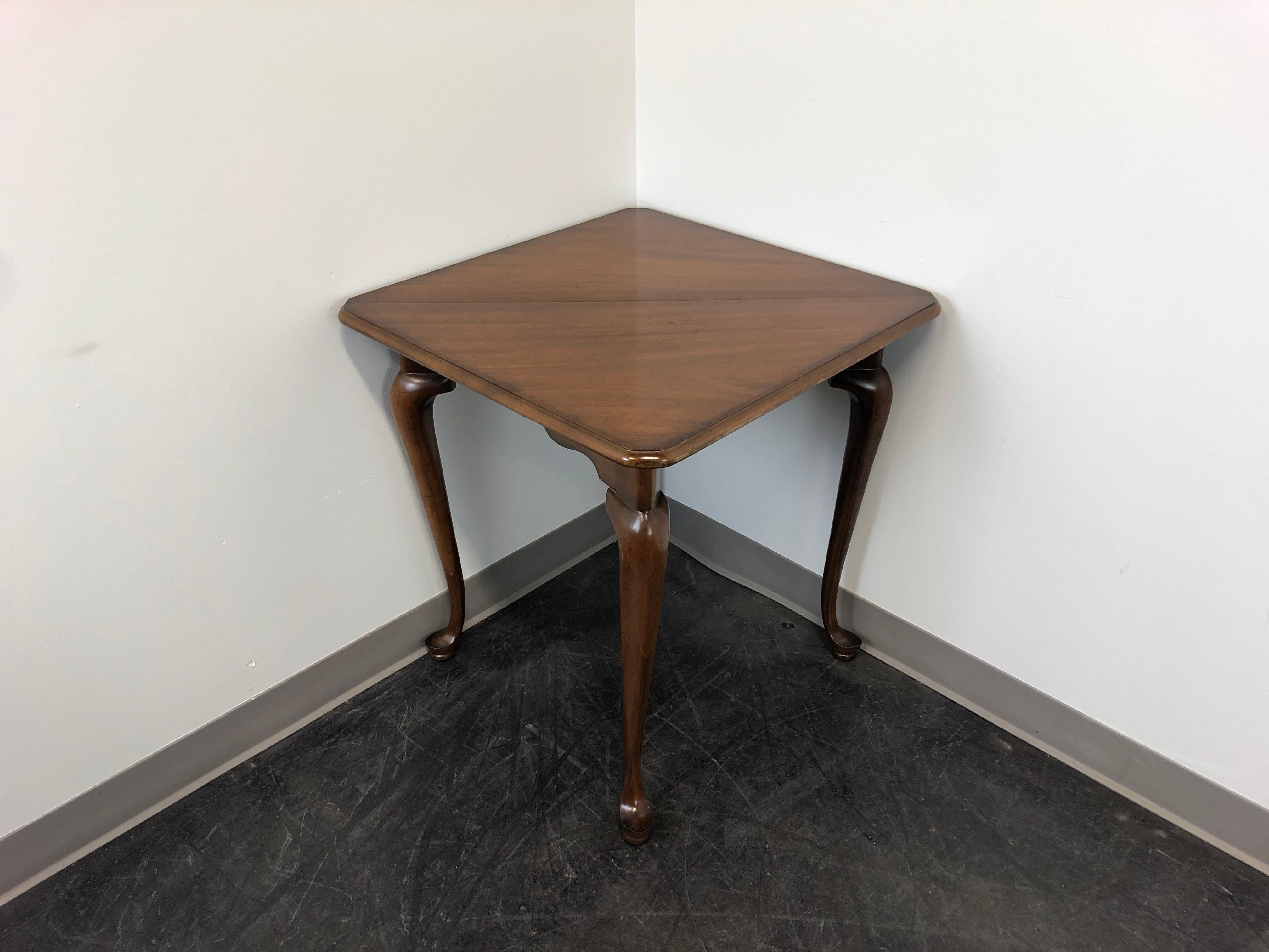 A drop-leaf handkerchief table in solid mahogany, unbranded, similar in quality to Baker and Kittinger. Queen Anne style with cabriole legs and pad feet. Features a gate leg that swings out to support the drop-leaf when raised. Made in the USA, in