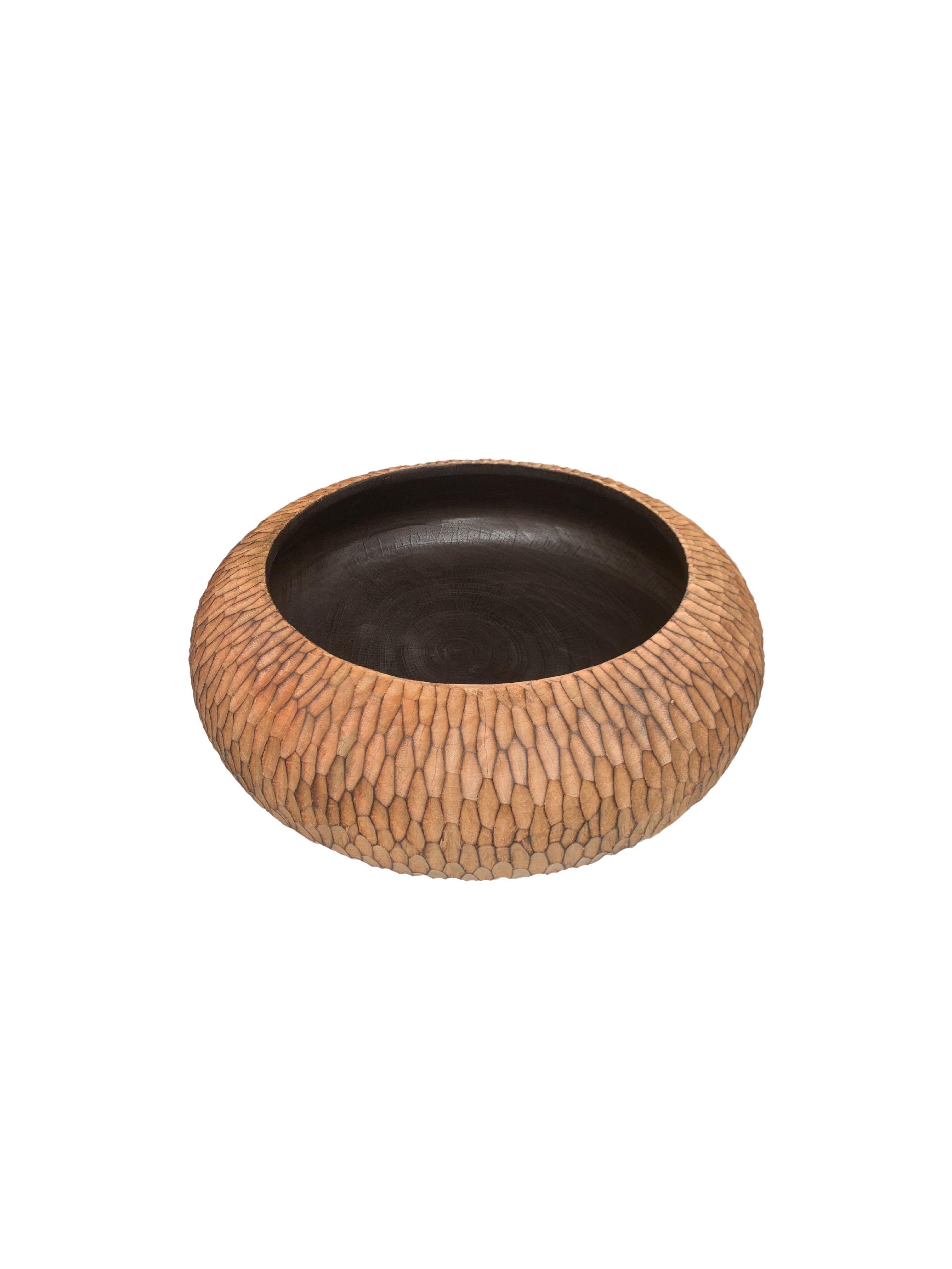 Un bol en bois de manguier fabriqué à la main. Le bol a été découpé dans une dalle de bois de manguier beaucoup plus grande et présente une texture taillée à la main sur ses côtés. Ce bol a été brûlé trois fois pour obtenir la riche couleur noire