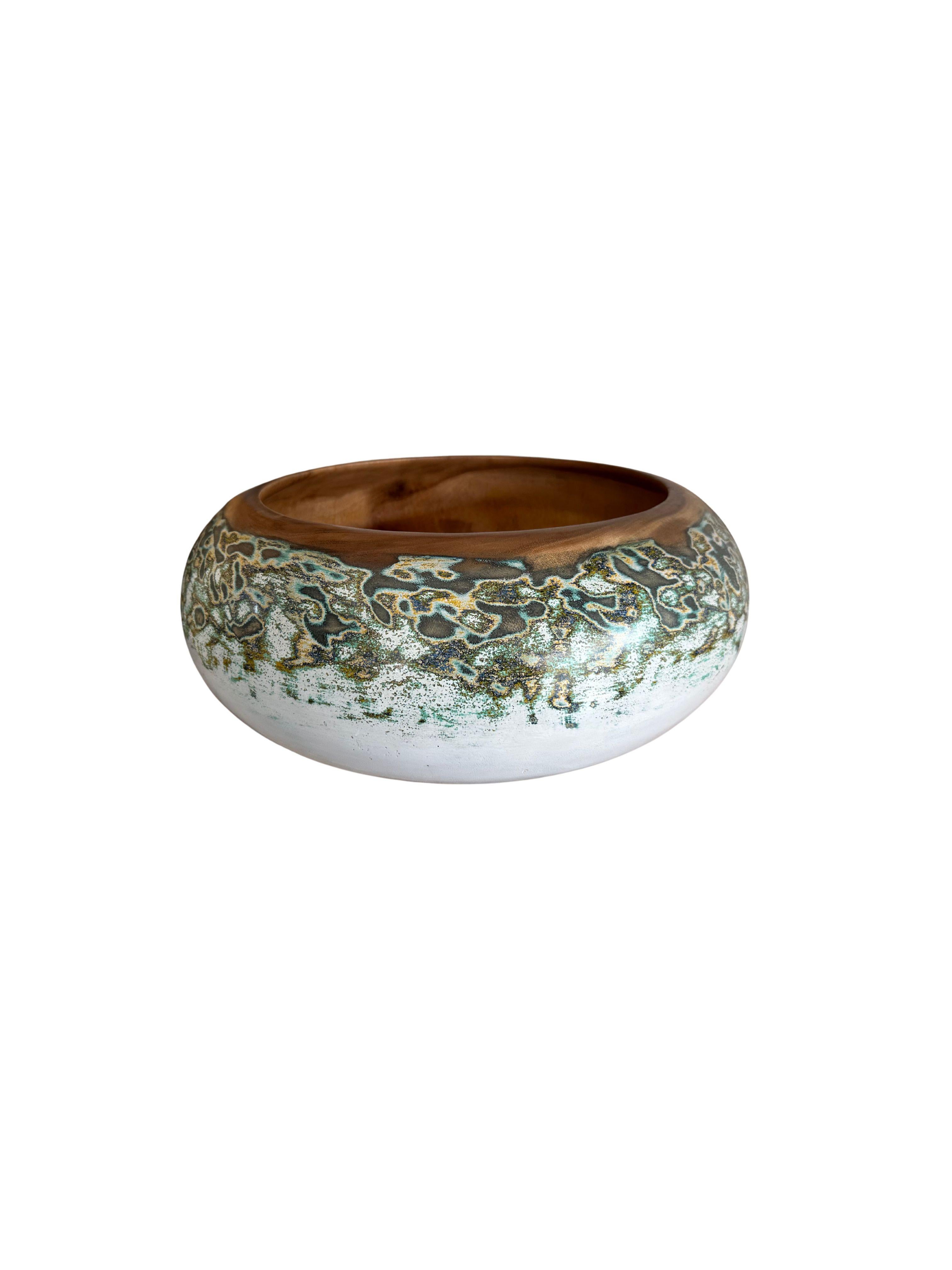 Un bol en bois de manguier fabriqué à la main. Le bol a été découpé dans une plaque de bois de manguier beaucoup plus grande et présente des détails peints à la main sur ses côtés, qui sont ensuite poncés pour obtenir une texture unique. Le bol est