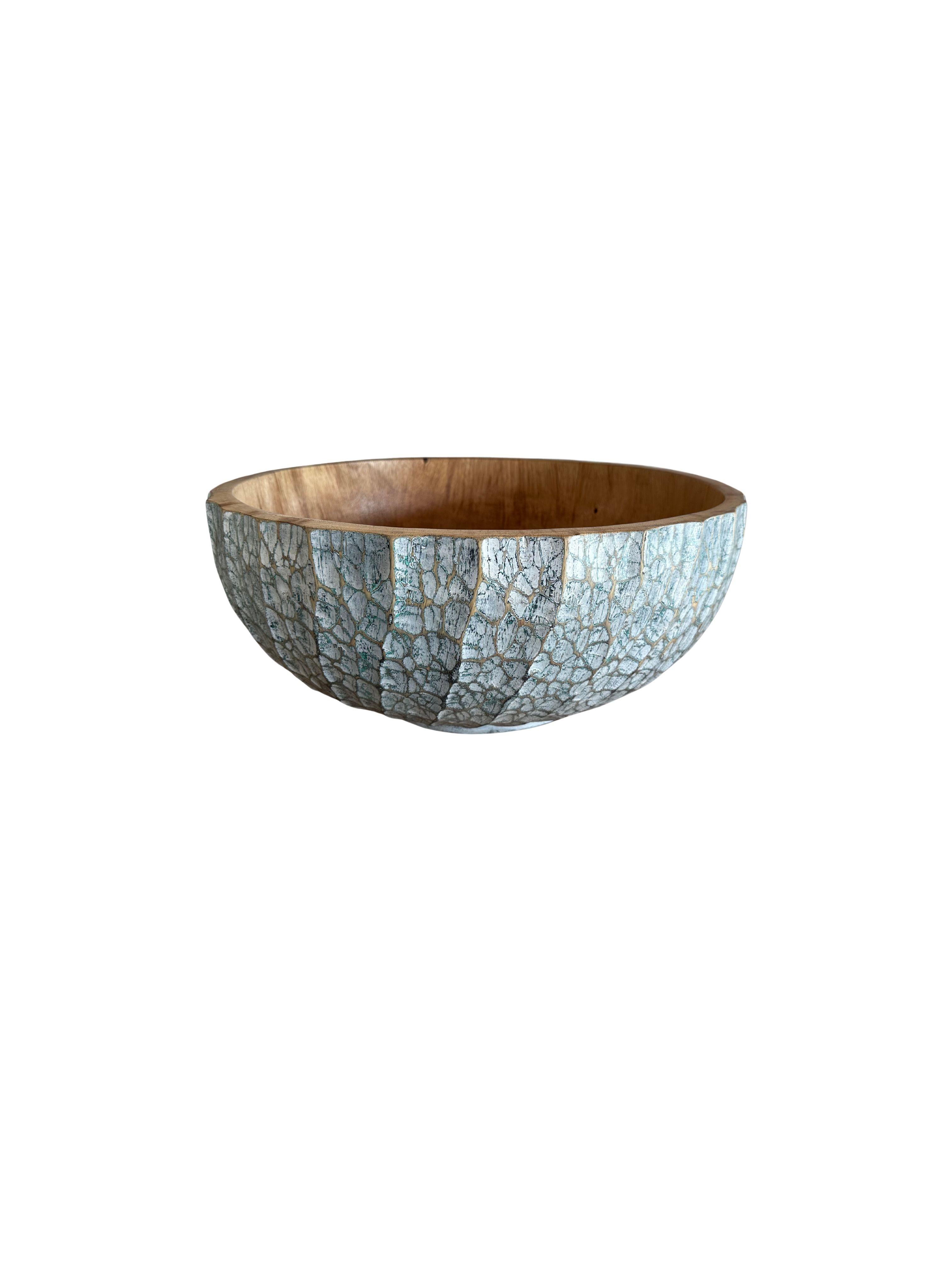 A hand-crafted mango wood bowl. The bowl was cut from a much larger slab of mango wood and features a hand painted detailing on its sides that is then sanded down to achieve a unique texture. This bowl also features hand-carved detailing providing