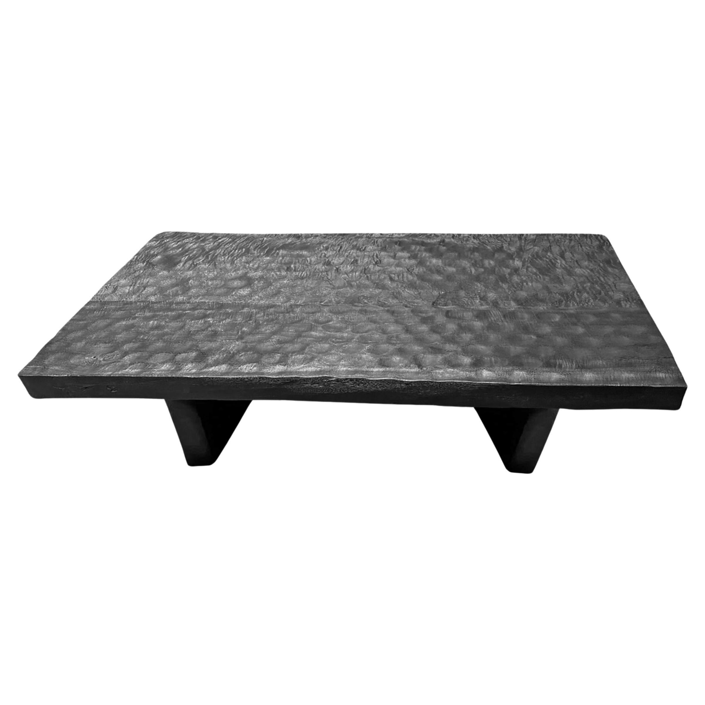 Cette table basse remarquable est fabriquée en bois de manguier, mettant en valeur la beauté naturelle du grain du bois tout en présentant une finition unique en noir brûlé qui ajoute un air de sophistication et de charme rustique. Les détails