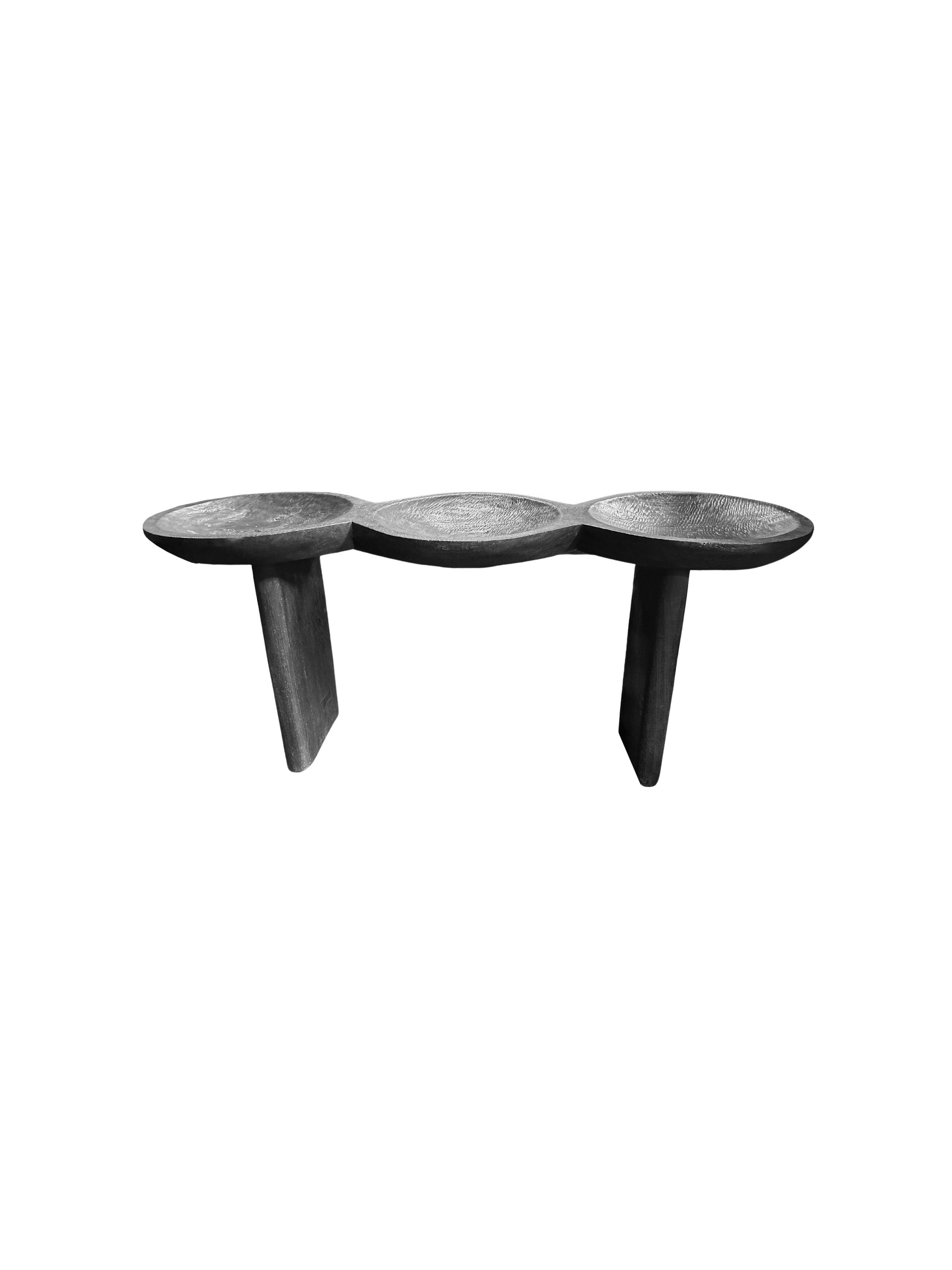 A sculptural mango wood console table crafted from solid mango wood. The table top sits atop four slender legs. The tables legs are angular and feature curved edges providing a wonderful mix of curved and straight lines to the table. The subtle wood
