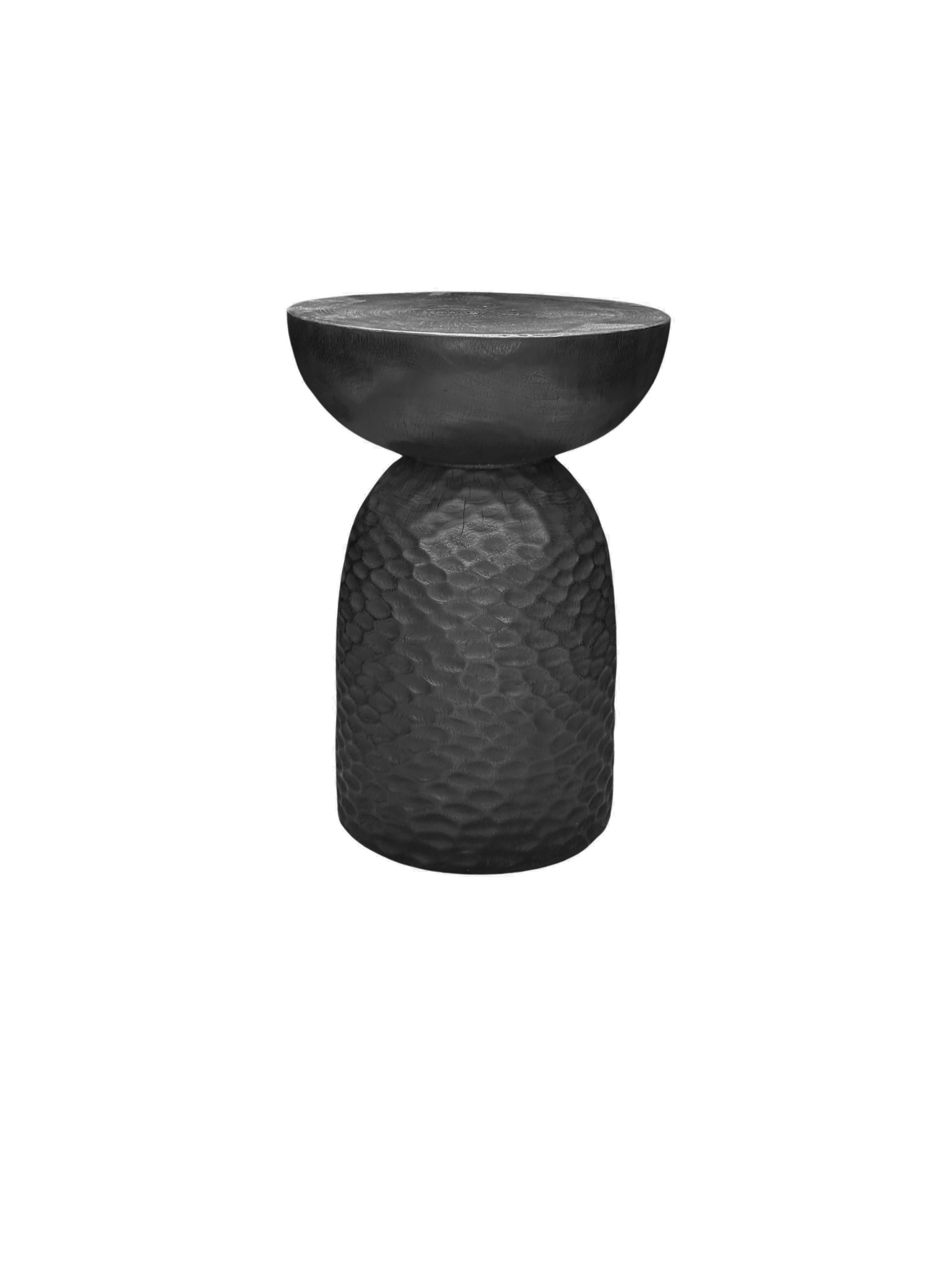 A wonderfully sculptural round side table, with an hourglass shape. Its neutral pigments make it perfect for any space. A uniquely sculptural and versatile piece certain to invoke conversation. It was crafted from a solid block of mango wood and has