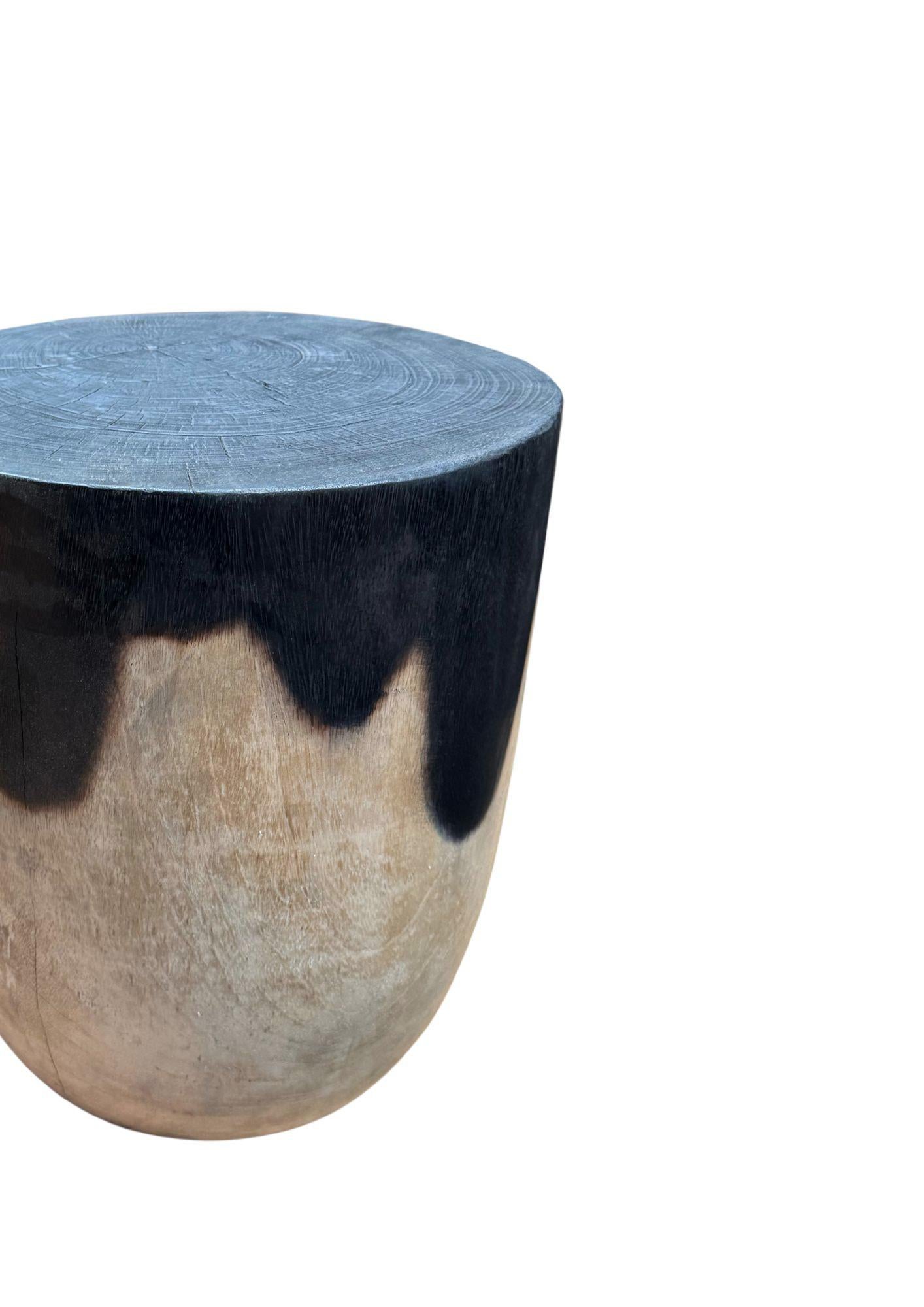 Elevate your space with this striking round mango wood side table, crafted to showcase the natural beauty and unique character of solid wood. Its distinctive two-tone finish features a dramatic black upper section created through an artisanal