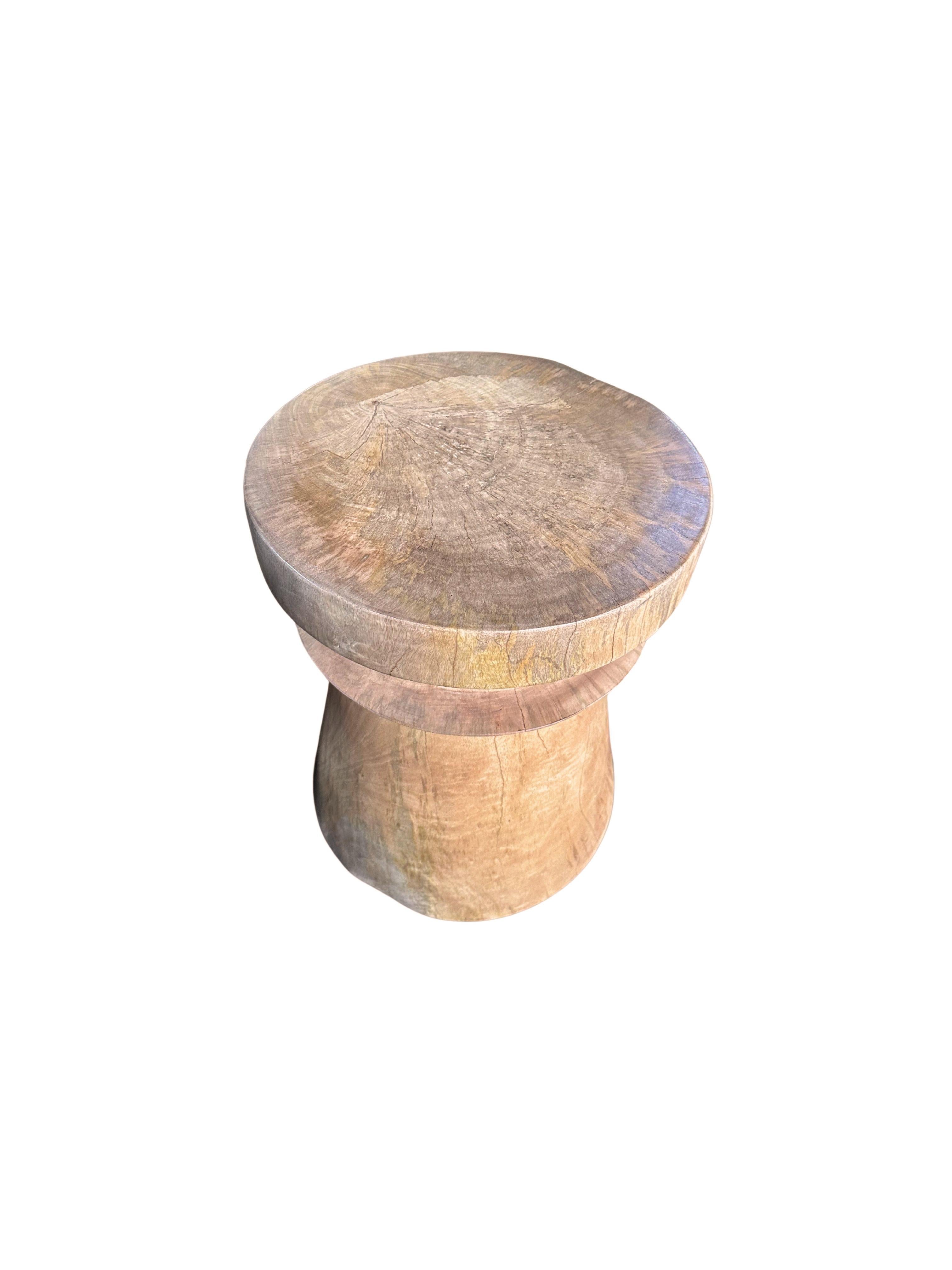 A wonderfully sculptural round side table. Its neutral pigments make it perfect for any space. A uniquely sculptural and versatile piece certain to invoke conversation. It was crafted from a solid block of mango wood and has a smooth texture natural