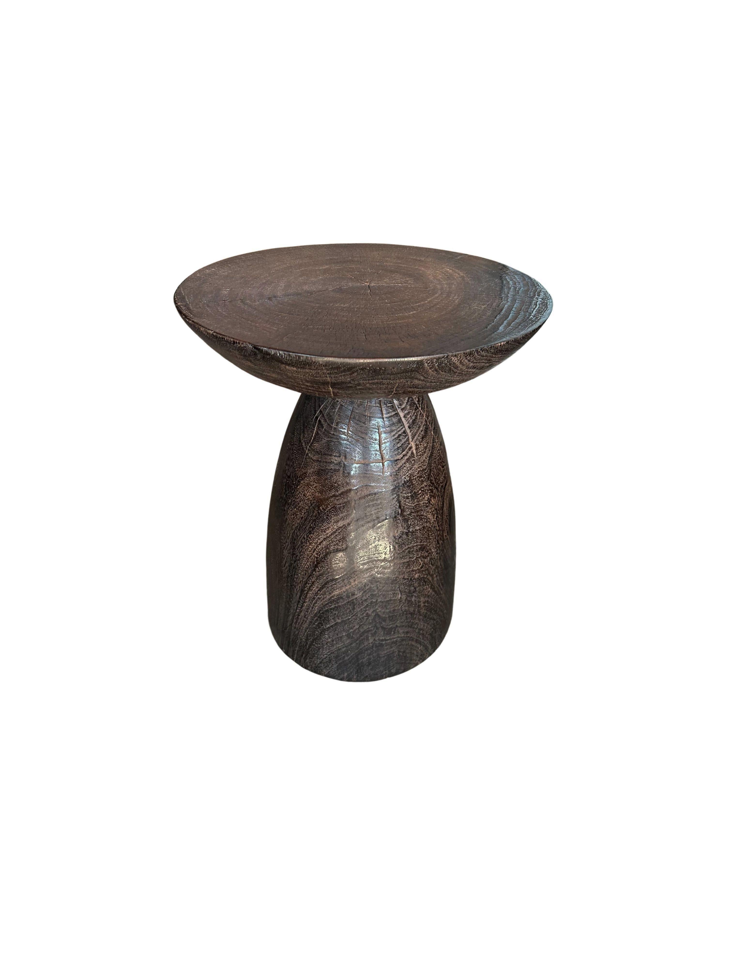 A wonderfully sculptural round side table, with an hourglass shape. Its neutral pigments make it perfect for any space. A uniquely sculptural and versatile piece certain to invoke conversation. It was crafted from a solid block of mango wood and has