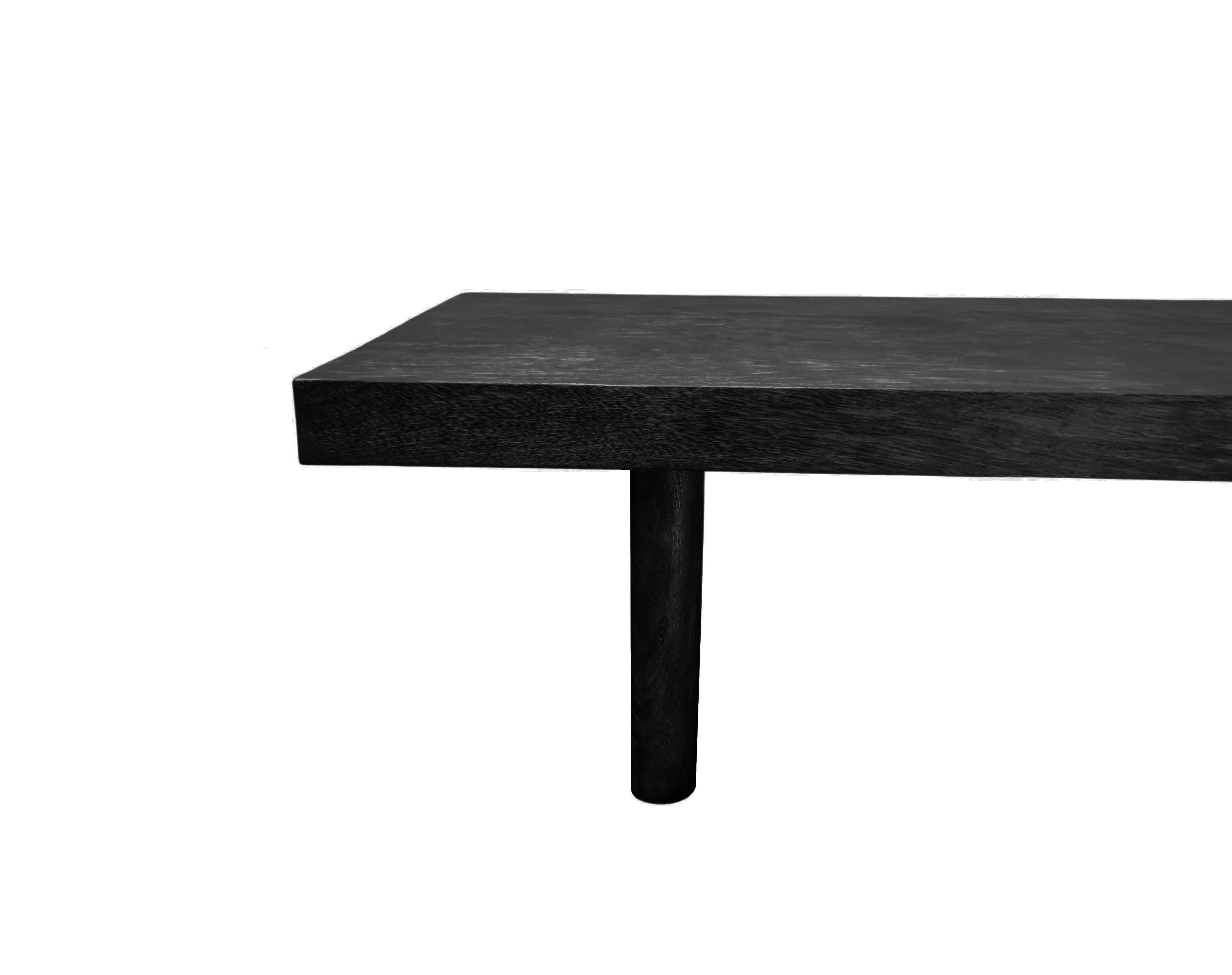 A solid mango wood sofa table with wonderful wood textures and shades. The table top is crafted from a solid slab of mango wood. The table also features two solid legs that span its width and feature curved sides. To achieve its black pigment, the