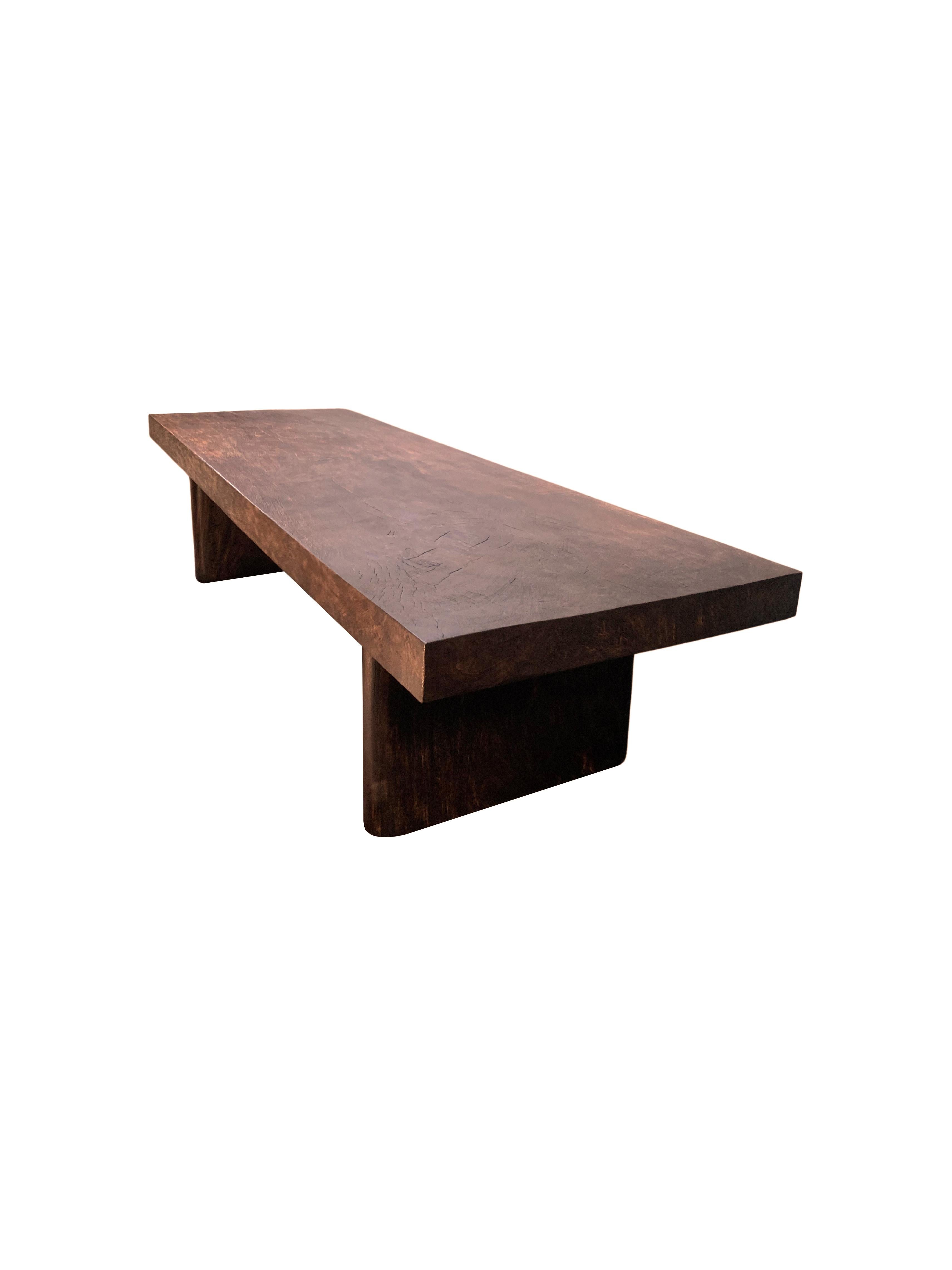 A solid mango wood sofa table with wonderful wood textures and shades. The table top is crafted from a soild slab of mango wood. The table also features two soild legs that span its width and feature curved sides. A wonderfully sculptural object,