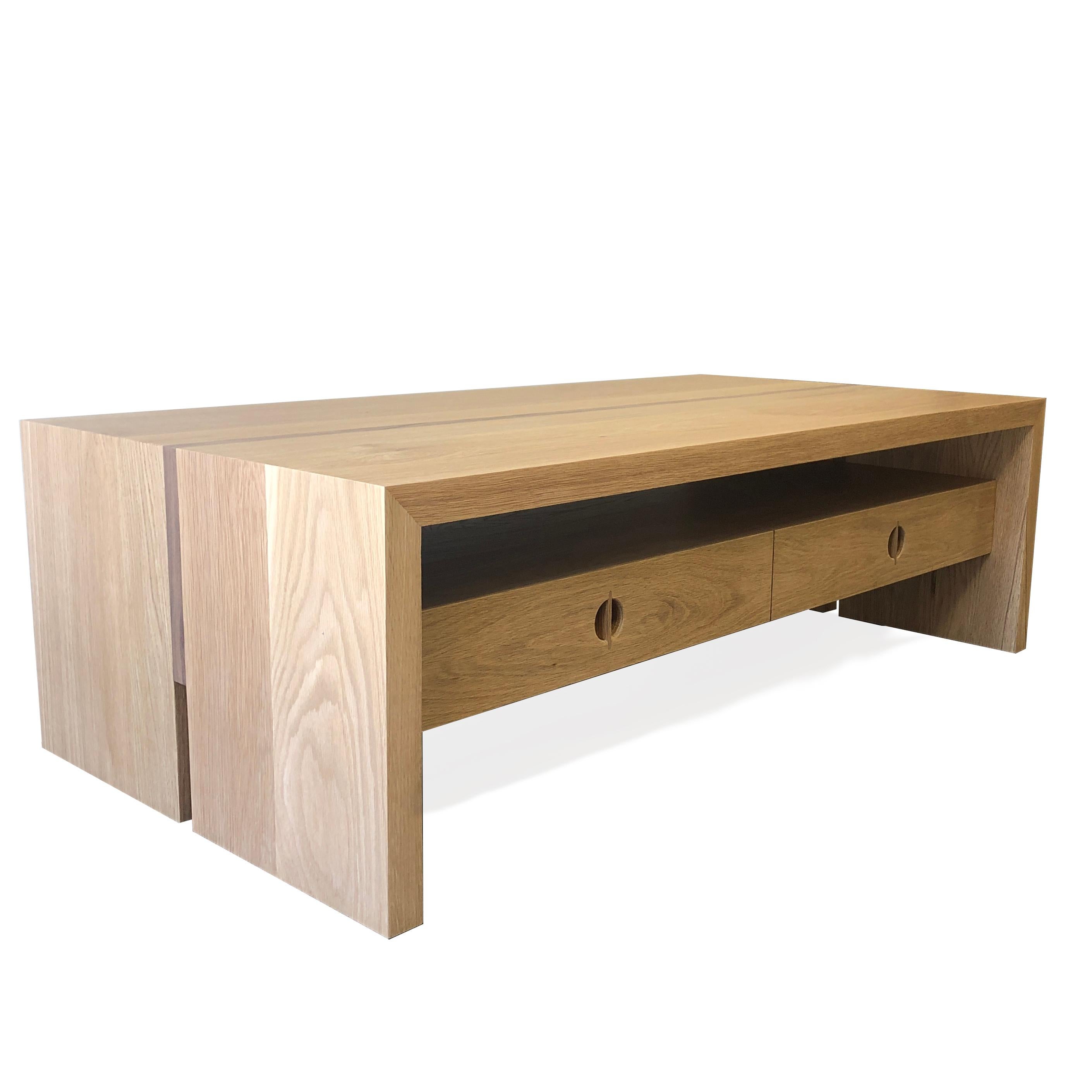 Cette table basse personnalisée est fabriquée à la main aux États-Unis avec du bois dur. Il présente un design carré moderne avec un corps en chêne blanc massif et un détail minimaliste de marqueterie en noyer. Les tiroirs de rangement pratiques et