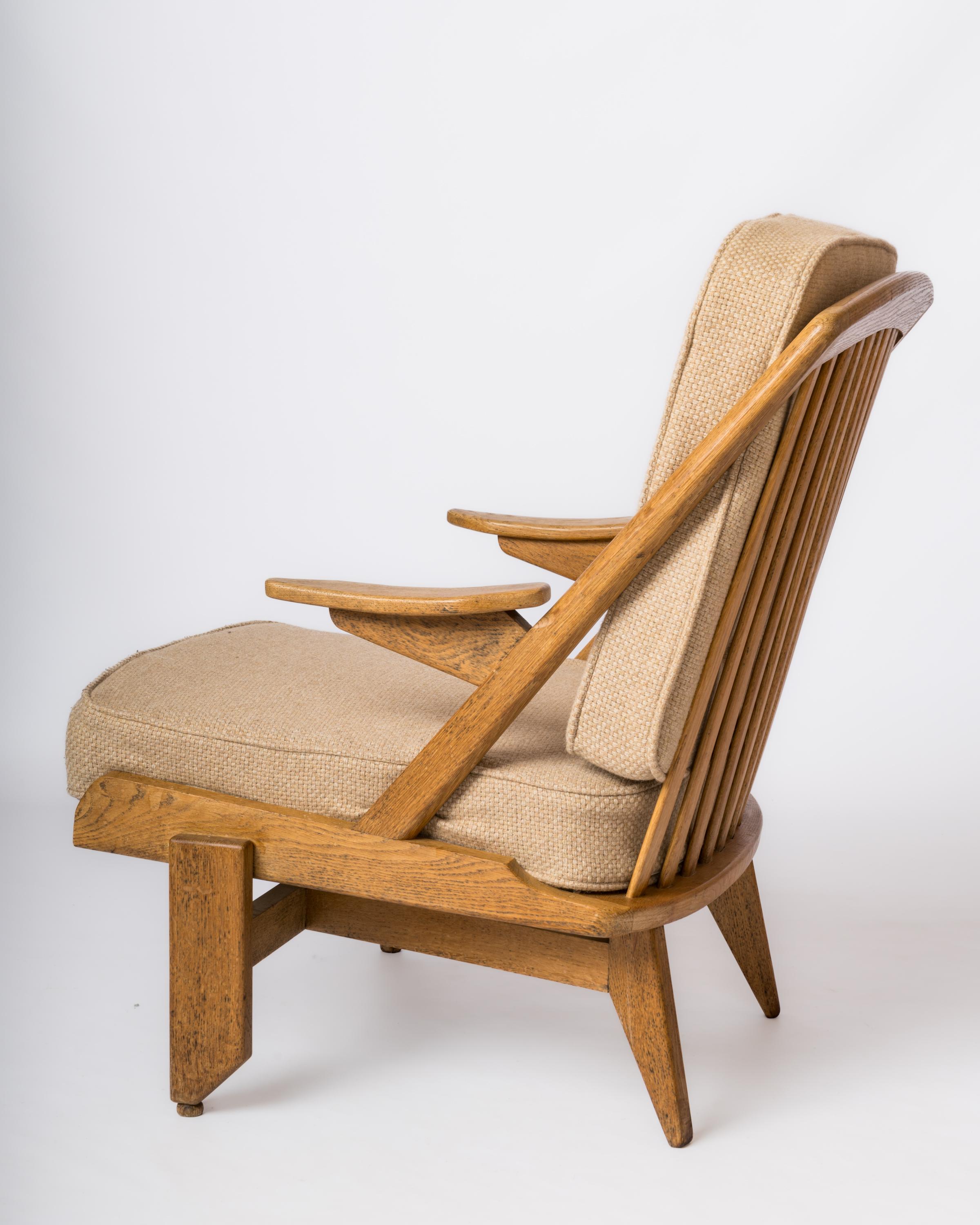 Elegant single all-oak armchair by Guillerme & Chambron featuring an openwork backrest.
Original cushions. 
Sturdy, wear and local stains on wood as shown on pictures.
This chair will ship from France and can be returned to France or to an upstate