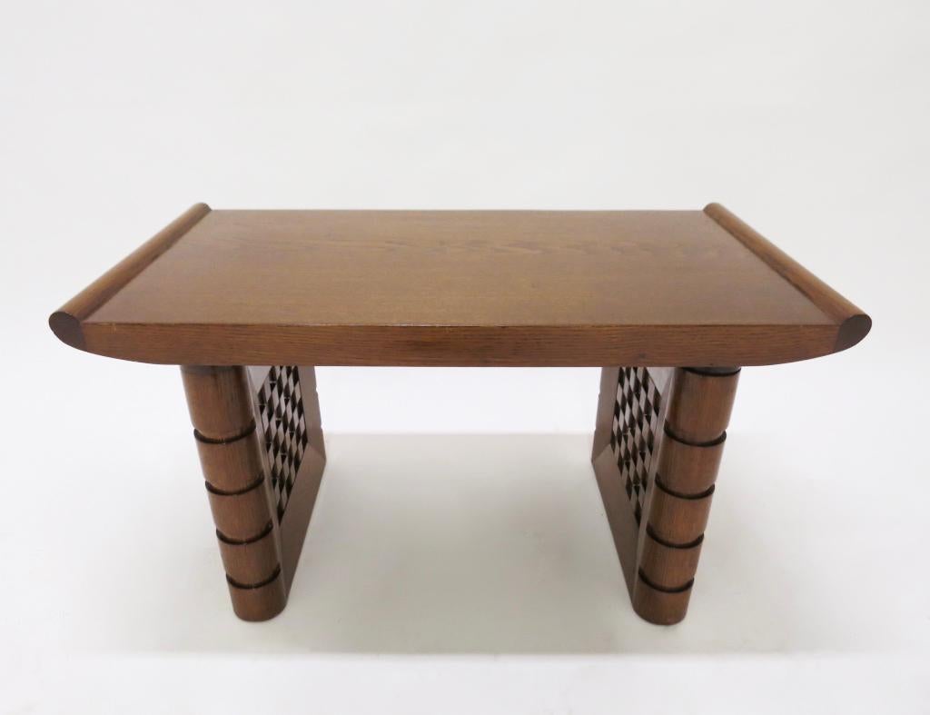 Strong and solid bench / stool in tiger oak by Charles Dudouyt comprises a flat top with flared, rounded edges that is supported on two, hand-carved dimensional legs with a centre checkered pattern on both sides and rounded outside edges that have