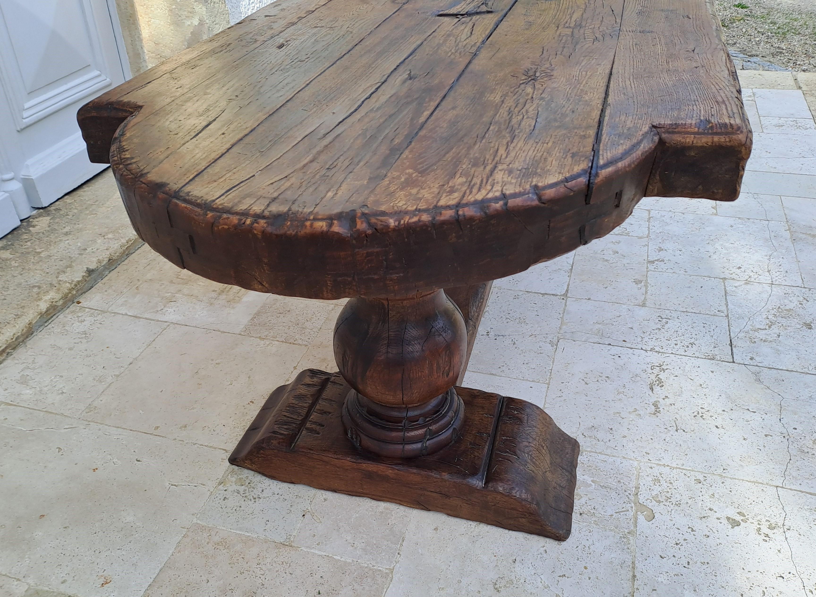 Imposing castle or monastery table in solid oak with a superb top in gendarme hats composed of five keyed planks and engraved in its center with a superb Occitan cross.
The base is composed of two enormous balusters connected by a lateral