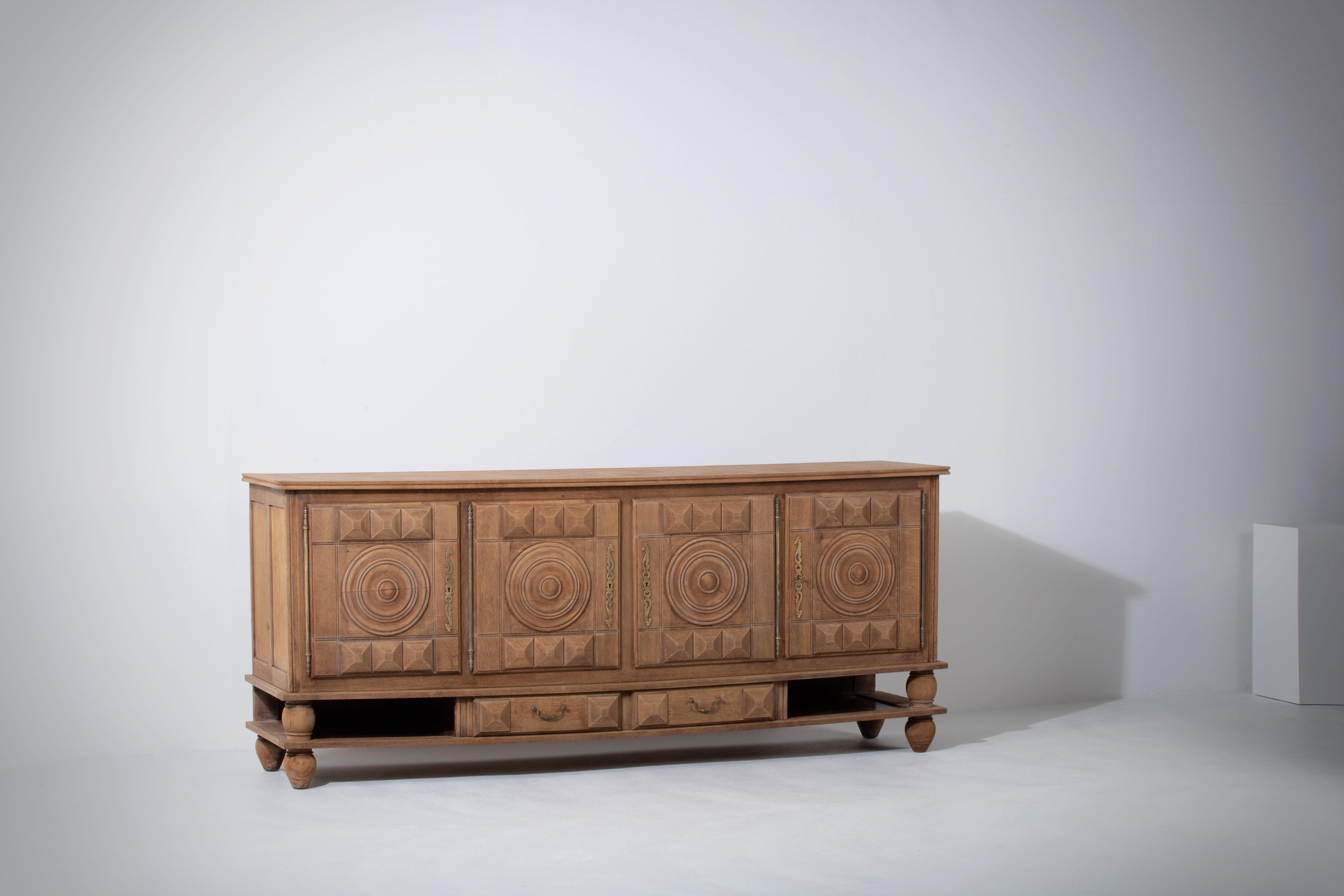 Large Credenza, solid oak, France, Charles Dudouyt, 1940s.
Large Art Deco Brutalist sideboard. 
The credenza consists of four storage facilities and covered with very detailed designed doors, in the center, drawers.
The refined wooden structures