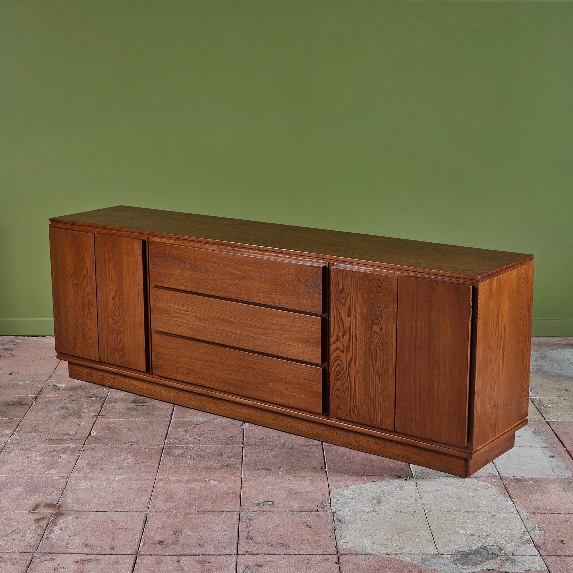 Solid Oak credenza features three drawers at the center of this case piece which are flanked by two door cabinets with interior shelving for additional storage. This piece is impressive in size with a length of 84