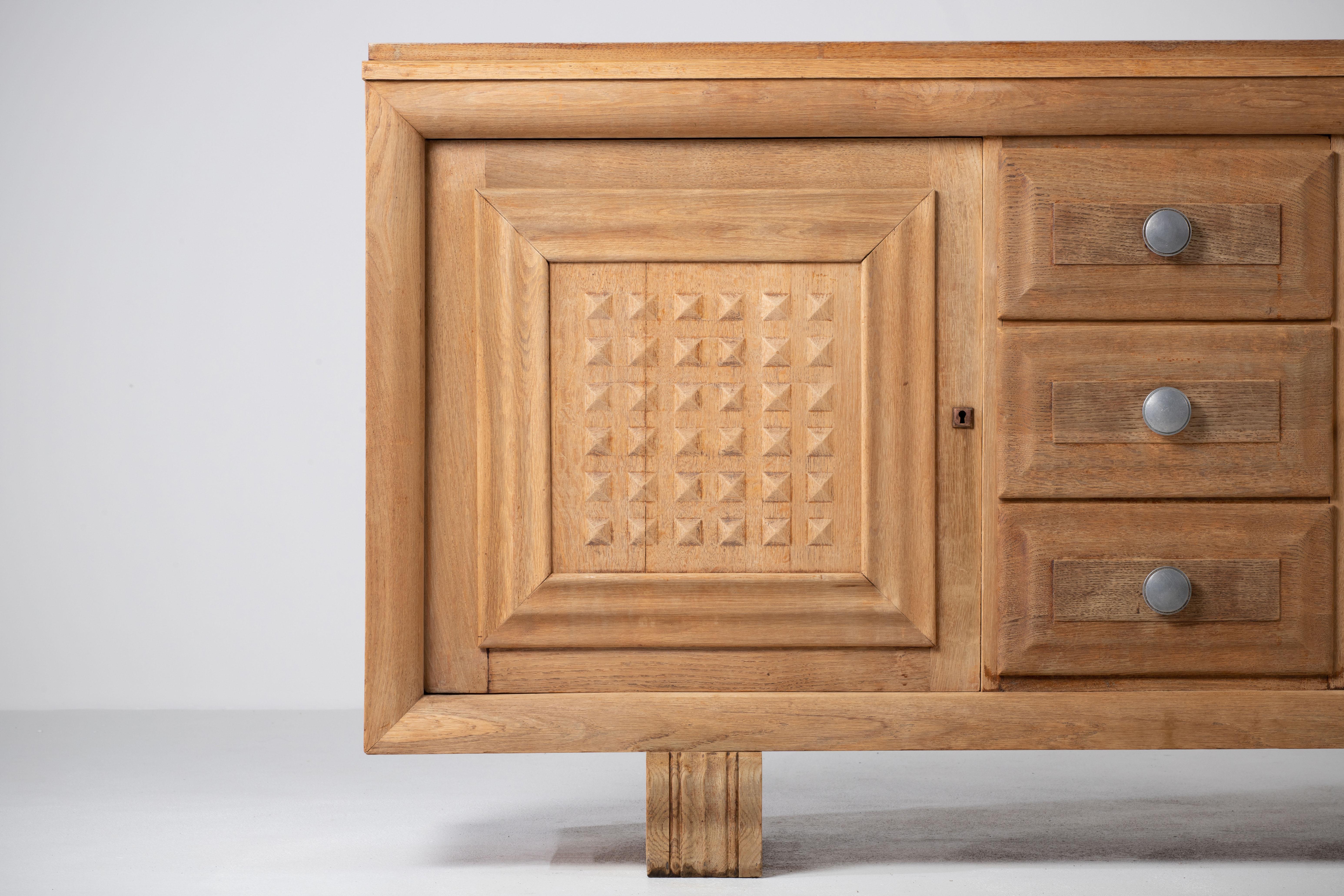 Credenza, solid oak, France, 1940s.
Large Art Deco Brutalist sideboard. 
The credenza consists of three central drawers and three storage facilities and covered with very detailed designed doors. 
The refined wooden structures on the doors create