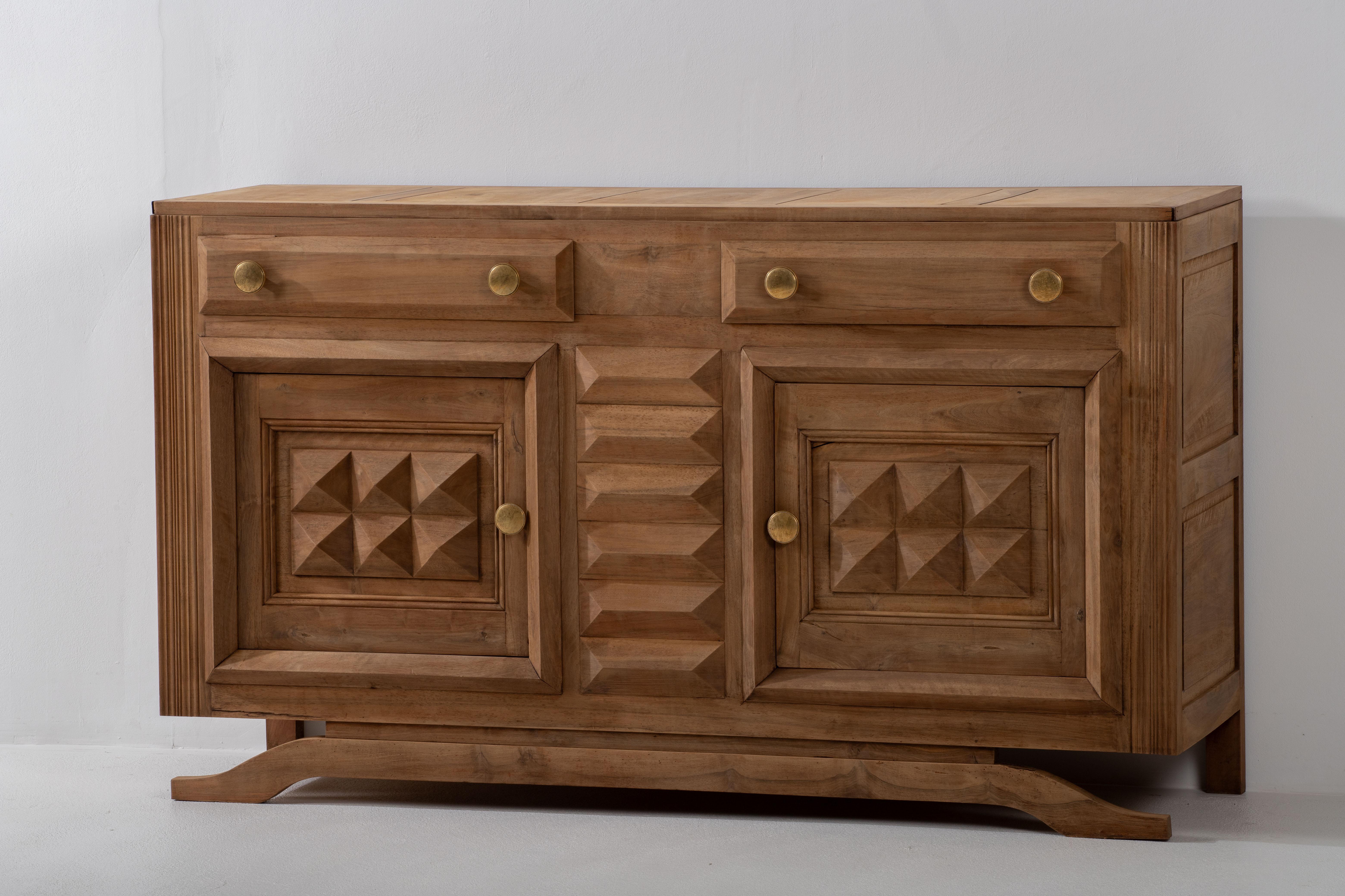 Presenting an exquisite credenza meticulously crafted from rich oak, echoing the artistic spirit of the 1940s. This Art Deco Brutalist sideboard features a symmetrical design with drawers thoughtfully positioned in the center. The piece offers two