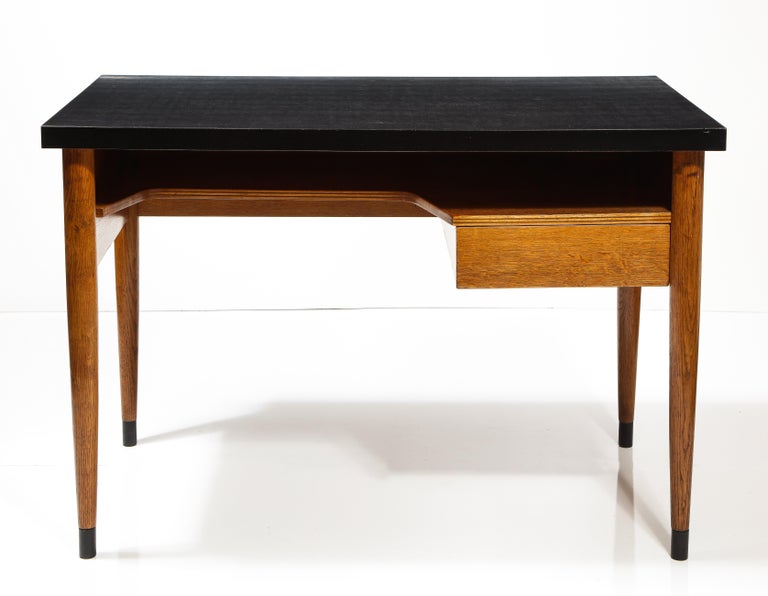 Solid Oak Desk by Raphael Raffel for Maison Internationale Paris, France, c. 1955. 

This elegant desk consists of a solid oak construction, dark formica top, and brass-capped feet. Originally made for the Maison Internationale Paris, this desk is
