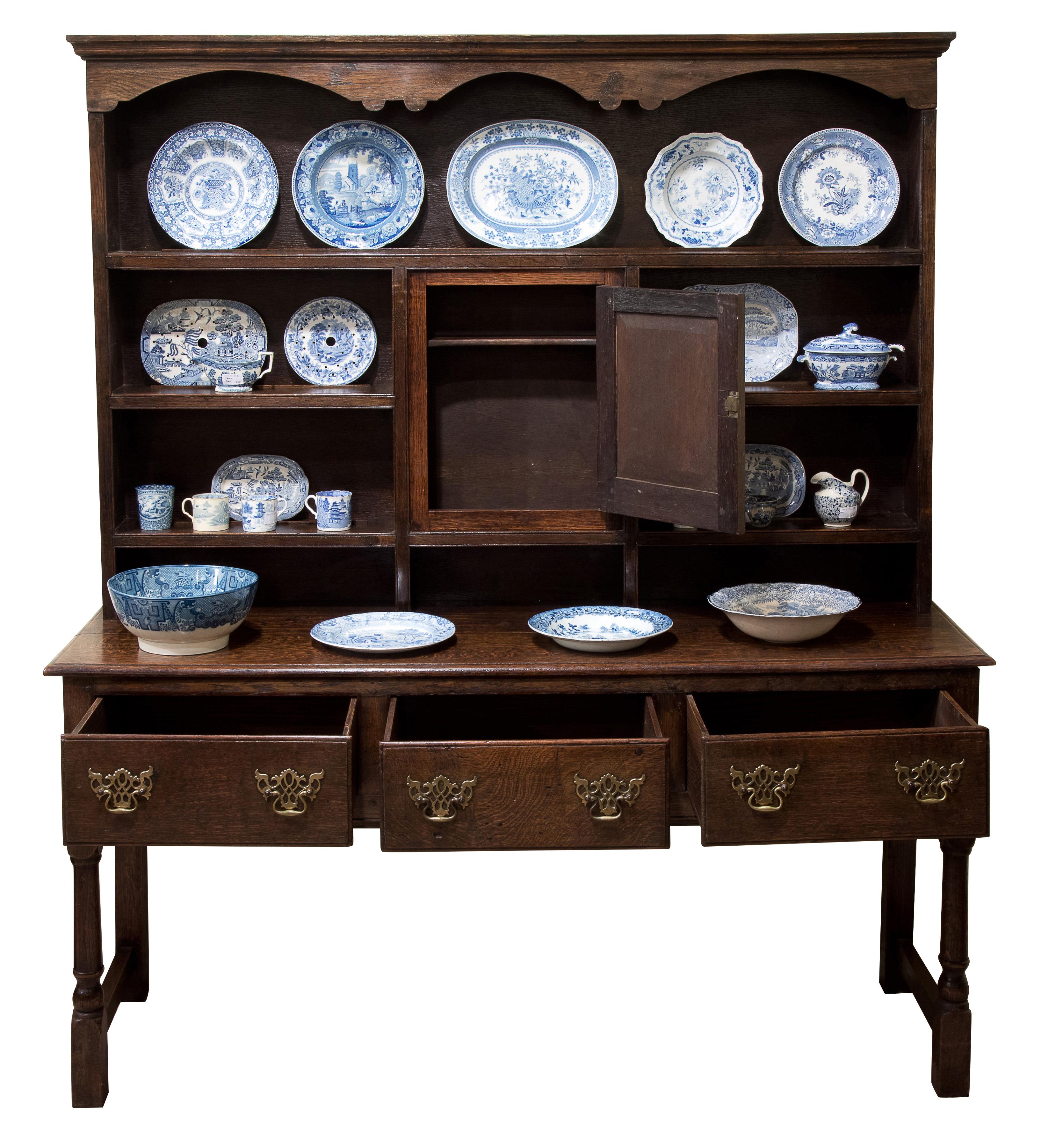 An English, solid oak dresser. The base fitted with three drawers. The plate rack incorporating a cupboard.

circa 1910.