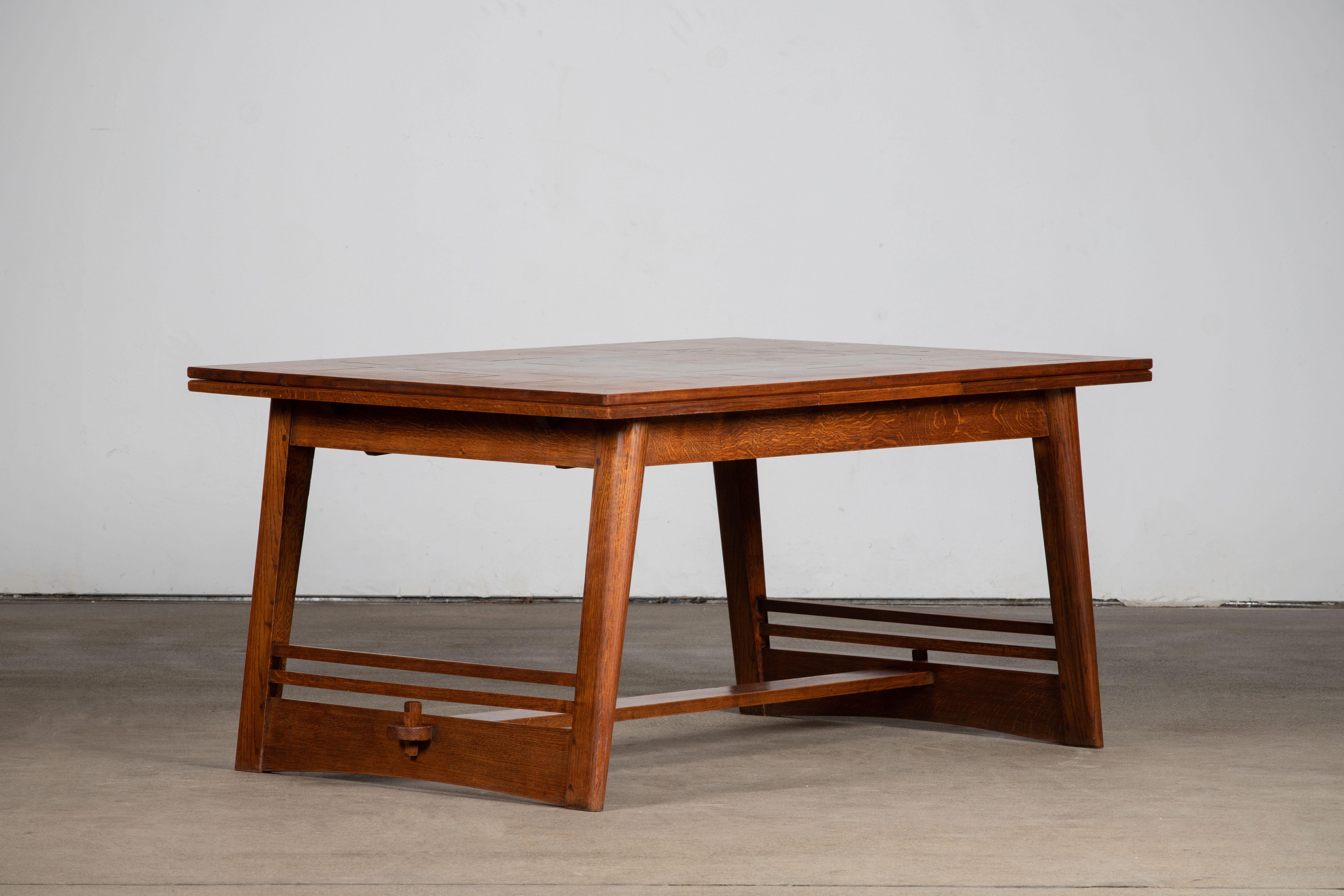 One of a kind French Art Deco solid oak dining table. The table features stunning oak wood grain with a stunning patina. The top is encrusted with a marquetry. 
It rests on tall and Brutalist tapered plein legs.
The table is in excellent original