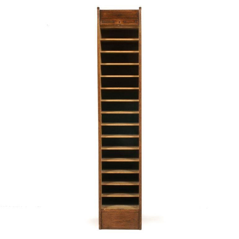 An unusually narrow, solid oak, tambour-front cabinet. Its size makes it very versatile throughout your home, circa 1910. Each of its fifteen interior compartment measures 12.5? wide x 12.5 deep x 3.5? tall.



