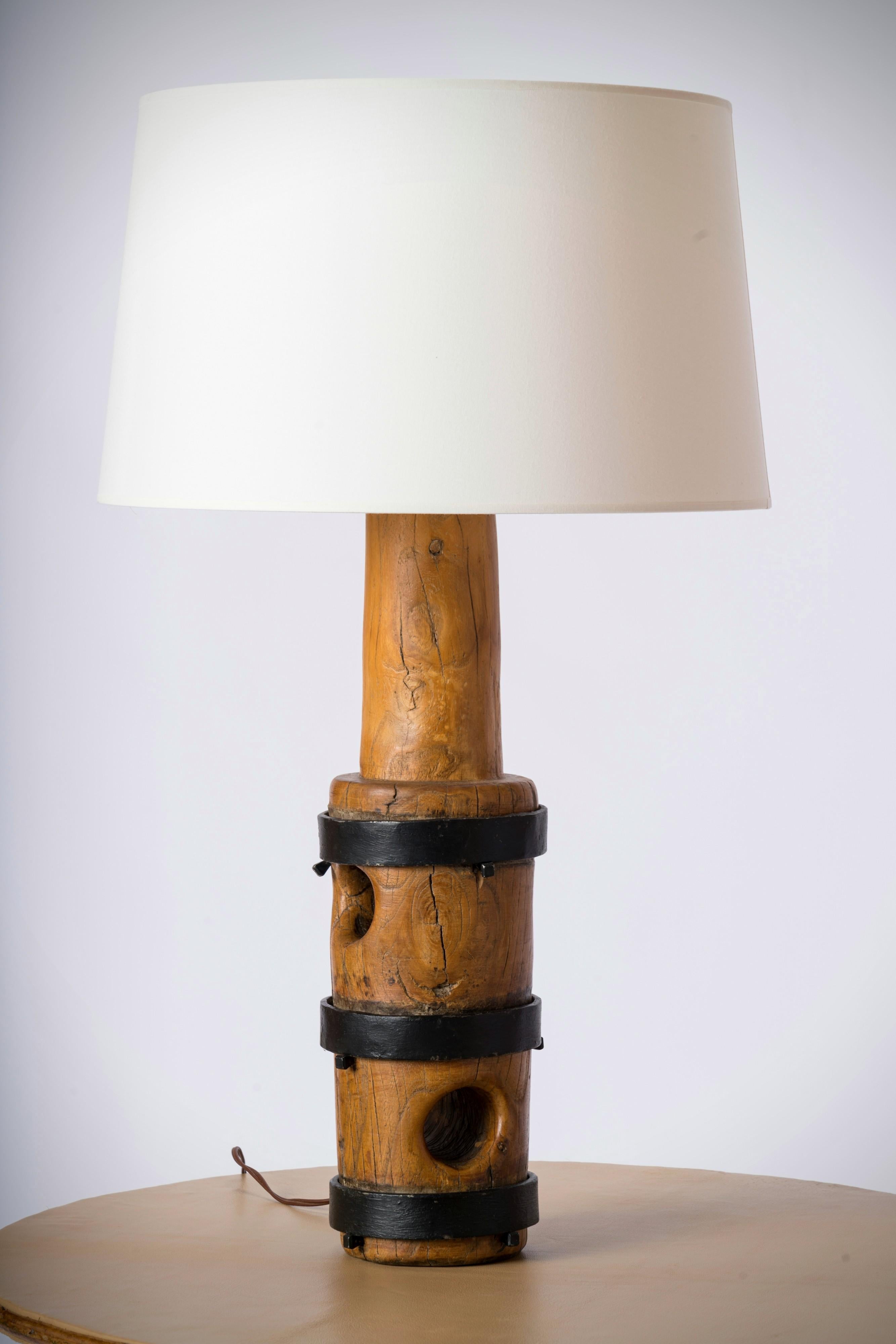 Big size solid oak sculptural table lamp with wrought iron strappings. Brutalist style. The core of the lamp features holes that add to the graphic impact of the lamp. An ideal accent piece that will blend in with either an urban or country house