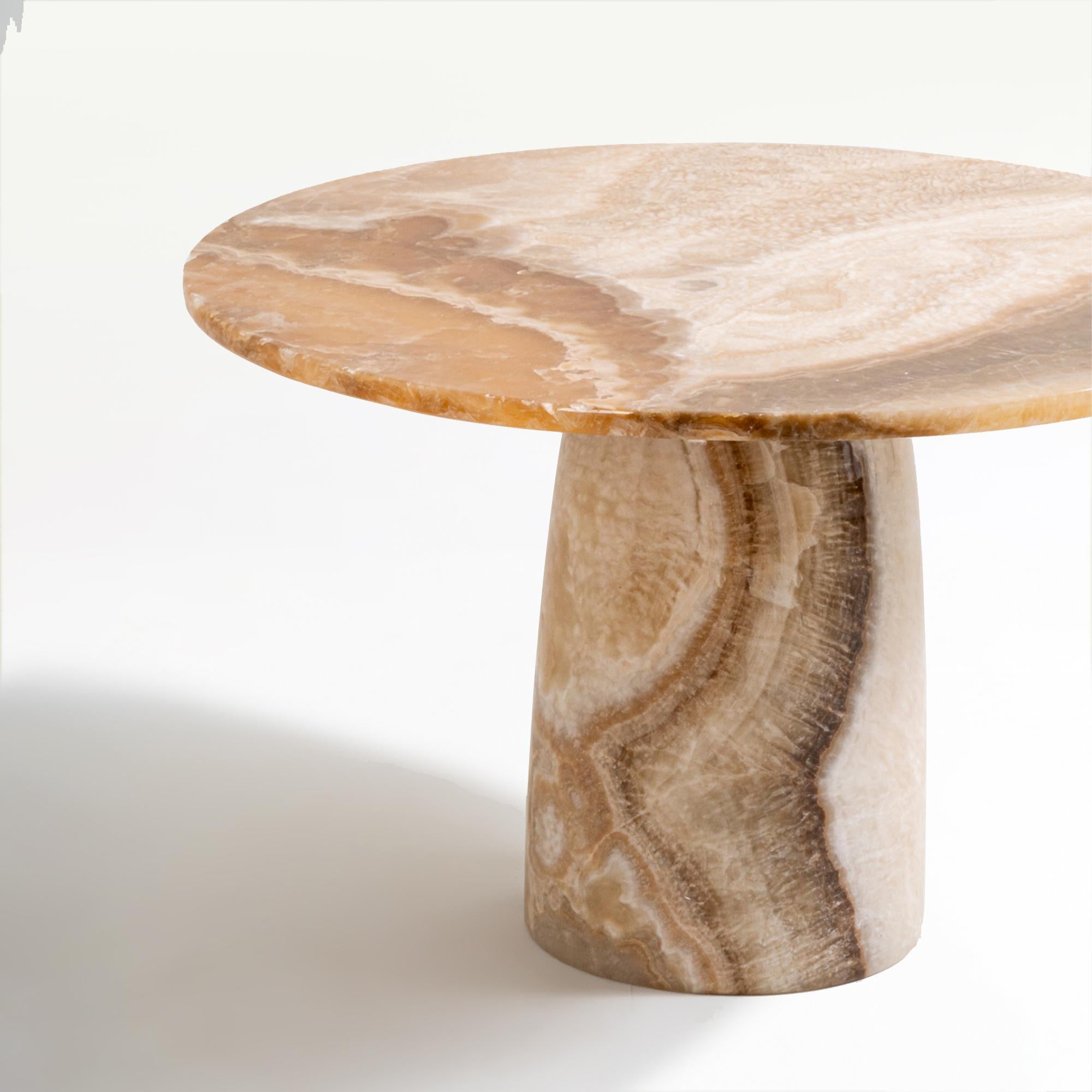 Voici la table basse Latte, une pièce simple en pierre d'onyx massif présentant des veines douces et élégantes. Disponible en deux variantes frappantes - un sommet rond ou une forme captivante de trèfle à quatre feuilles - chaque design met en