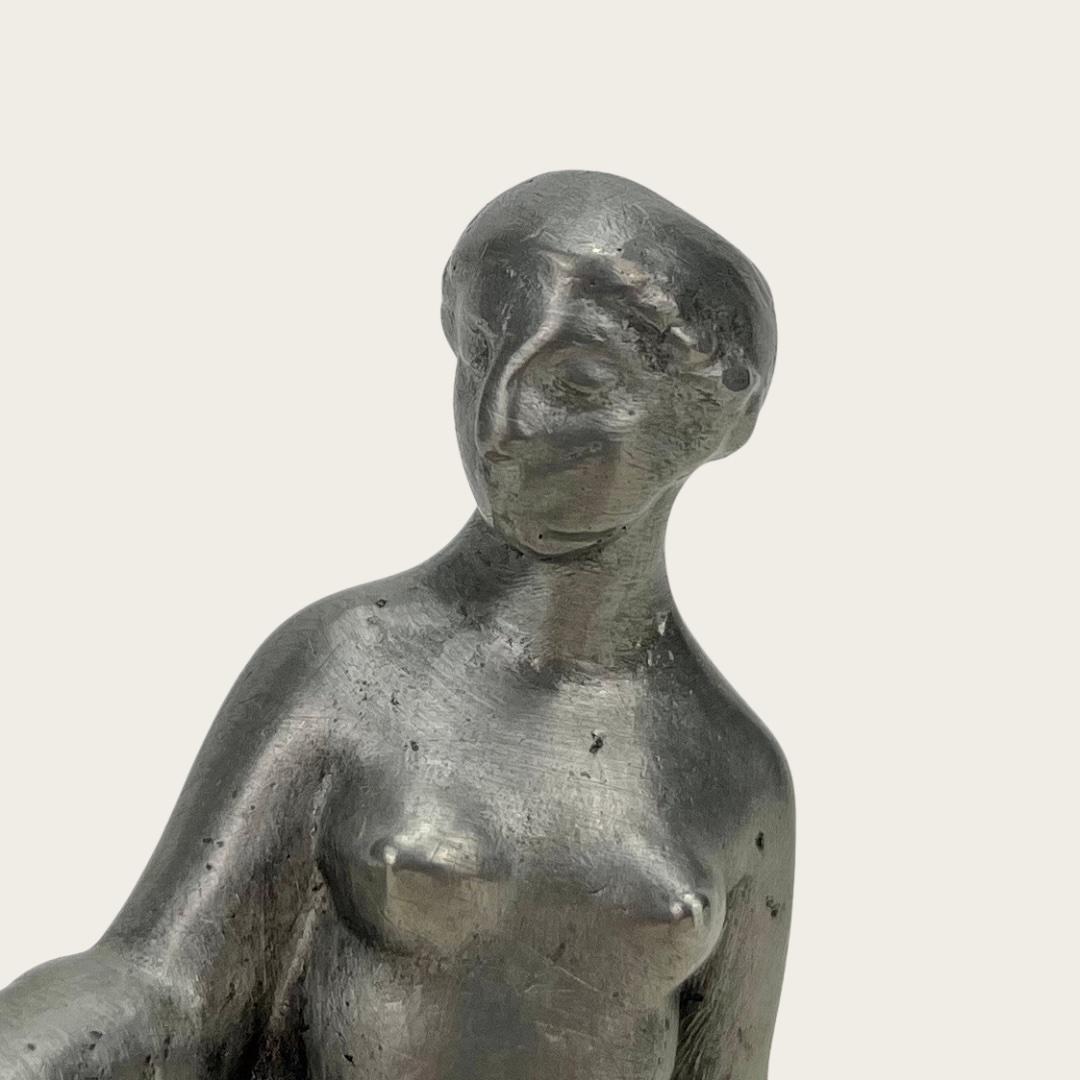Diese Skulptur aus massivem Zinn stellt eine nackte Frau im römisch-gräzistischen Stil aus den 1920er Jahren dar. Der Künstler ist unbekannt, aber auf der Unterseite des Stücks ist eine Signatur eingraviert.