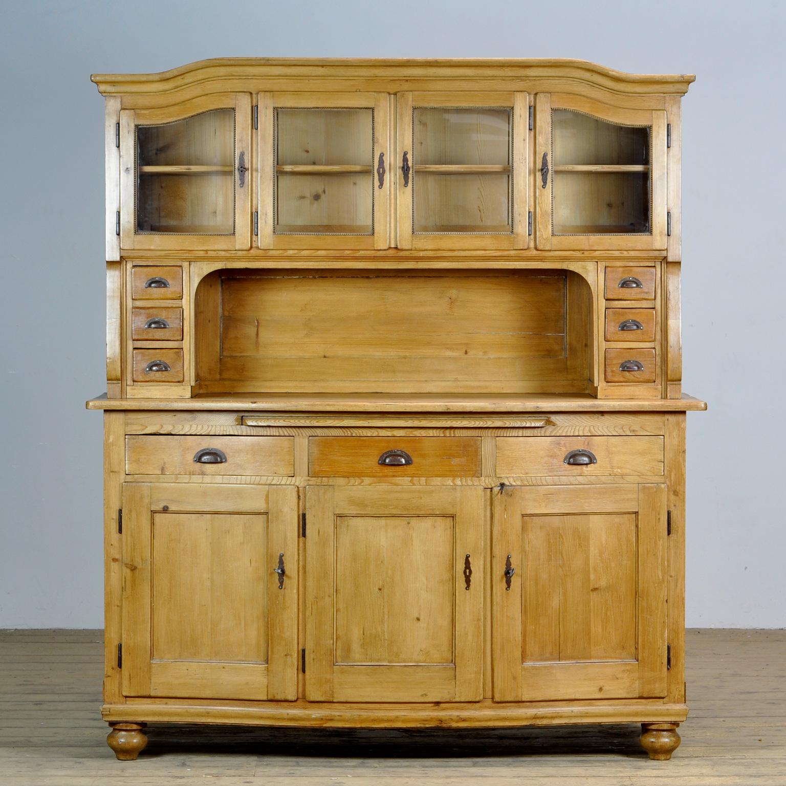 Antique German solid pine bread cabinet from circa 1925. The cabinet has a curved front with an extendable shelf for cutting bread. Lots of storage space behind the 7 doors. Assembled with dovetail joints.
The cabinet consists of two separate parts