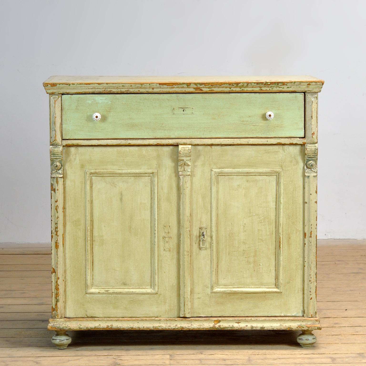 Aparador de pino de hacia 1910. El mueble conserva su pintura original con una hermosa pátina. El armario tiene una cerradura con llave que funciona bien. Este armario ha sido limpiado y tratado contra la carcoma. Un mueble bonito y práctico con