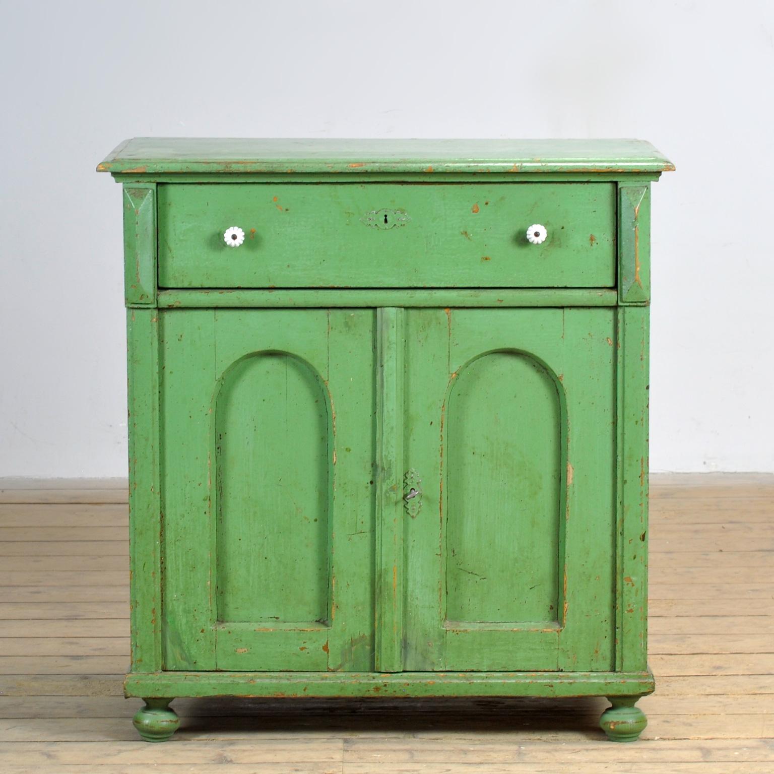 Aparador de pino de hacia 1910. El mueble conserva su pintura original con una hermosa pátina. El armario tiene una cerradura con llave que funciona bien. Este armario ha sido limpiado y tratado contra la carcoma. Un mueble bonito y práctico con