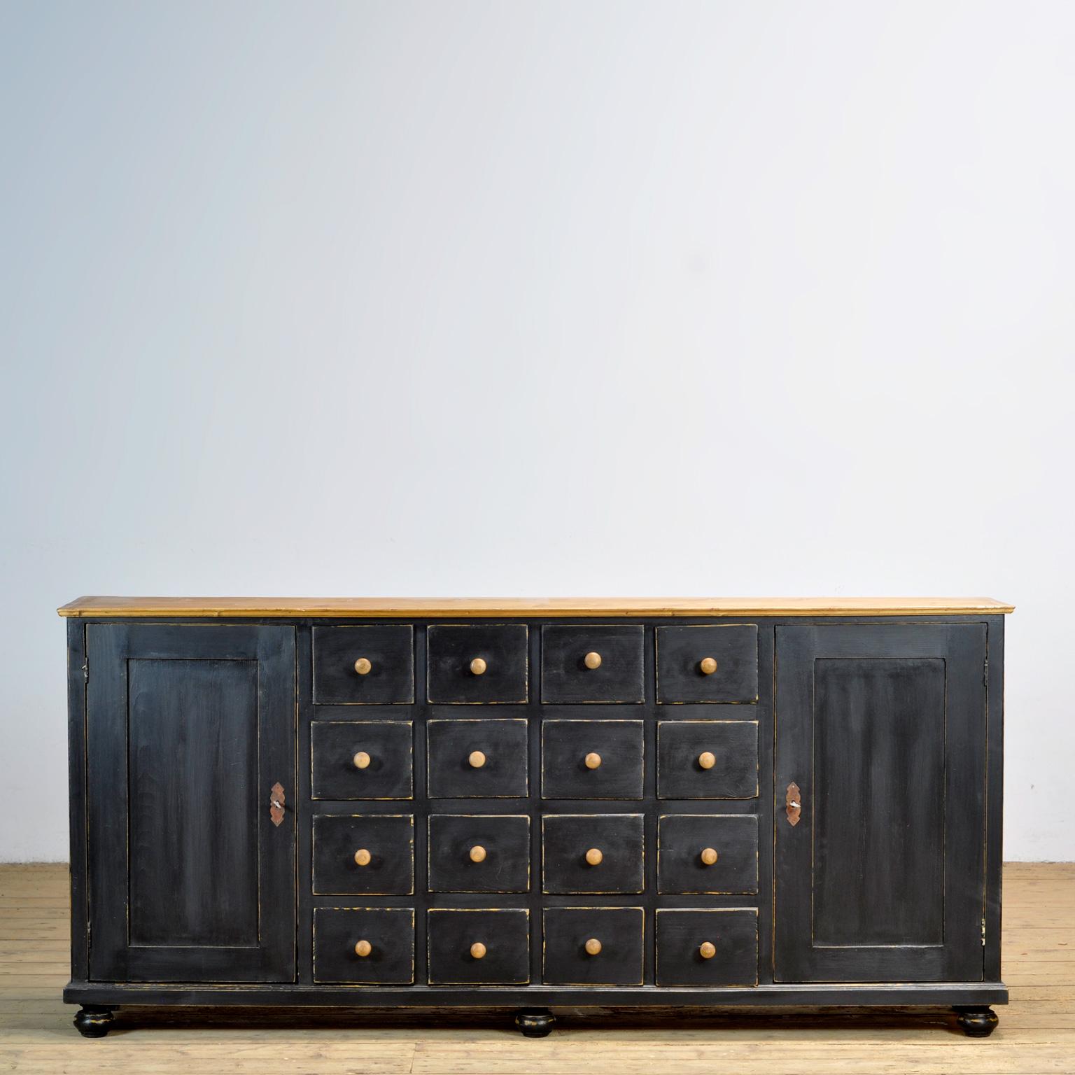 Base per comò in pino del 1920 circa con 16 cassetti e due ante con 2 ripiani dietro. Riverniciato in stile rustico. L'intero mobile è assemblato con incastri a coda di rondine. La credenza è in condizioni di restauro.