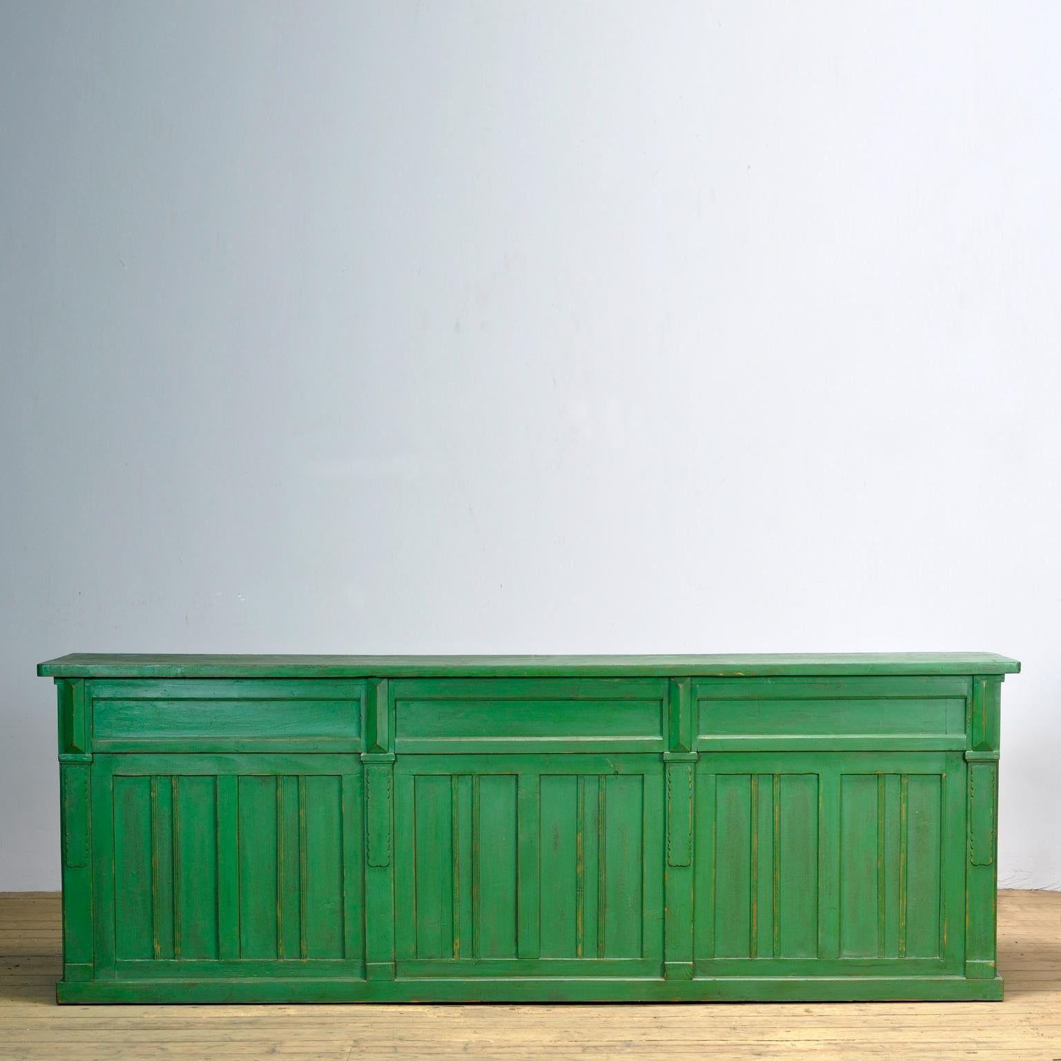 Large French shop counter – chest of drawers. A beautiful large French counter with nine drawers. Made of the solid pine wood. The green original paint gives the counter an exceptional color and character. Nice details on the front. The drawers are