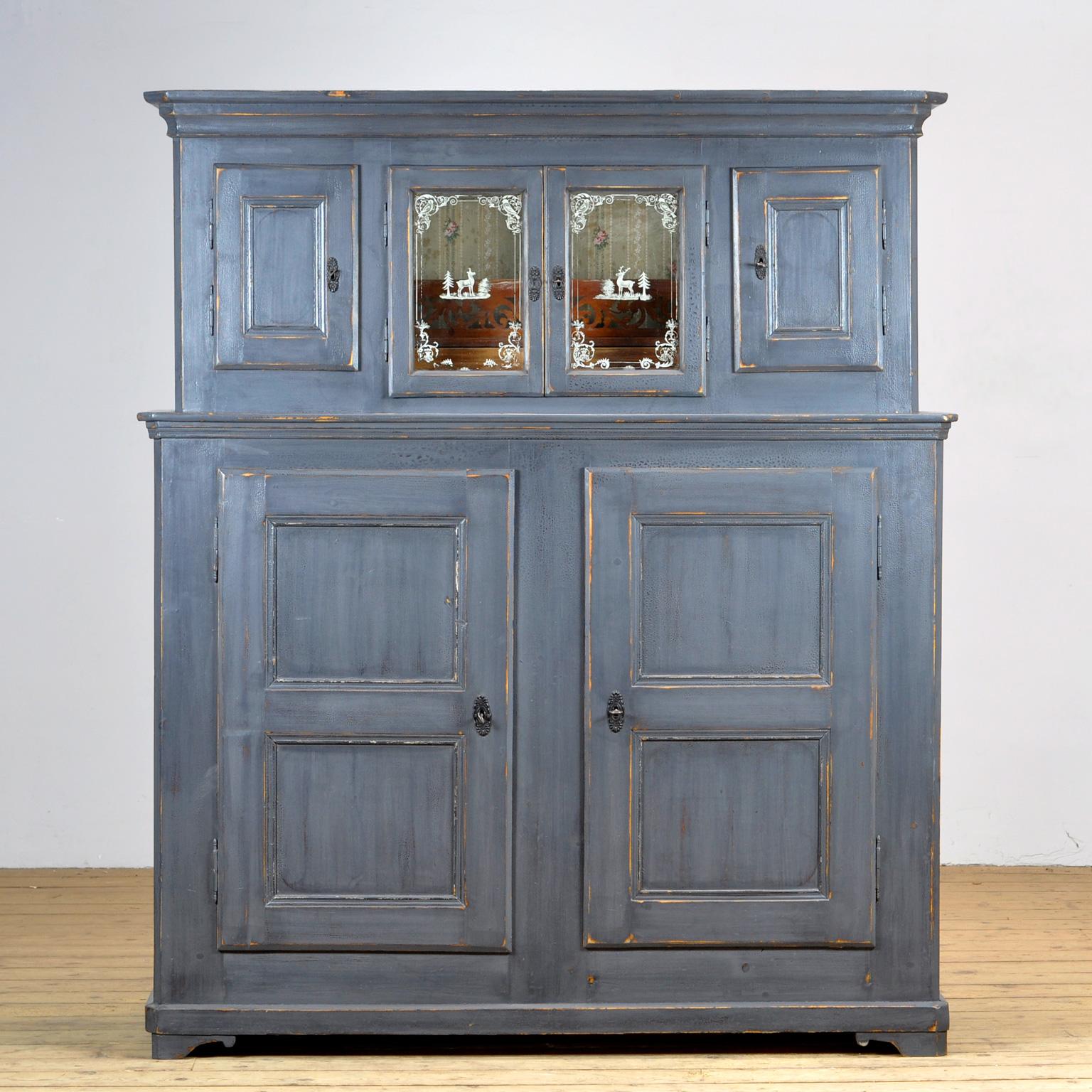 Solid pine cabinet from the 1920s. The cabinet consists of 2 separate parts. In the upper part 4 doors with a shelf and two drawers behind the two middle doors. The glass is hand painted. At the bottom 2 doors with a shelf for plenty of storage