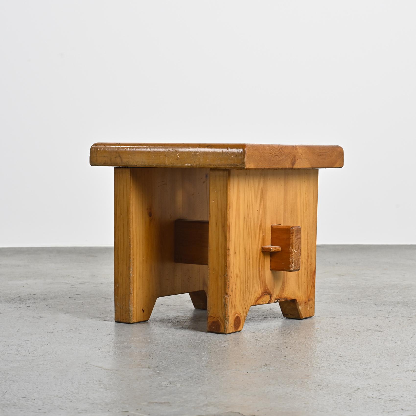 
Dieser kleine Hocker aus massivem Kiefernholz besticht durch seine schlichten Linien und die traditionelle Tischlerarbeit. Die quadratische Sitzfläche mit zentraler Öffnung ruht auf einem Sockel mit Zapfenverbindungen, der handwerkliches Können
